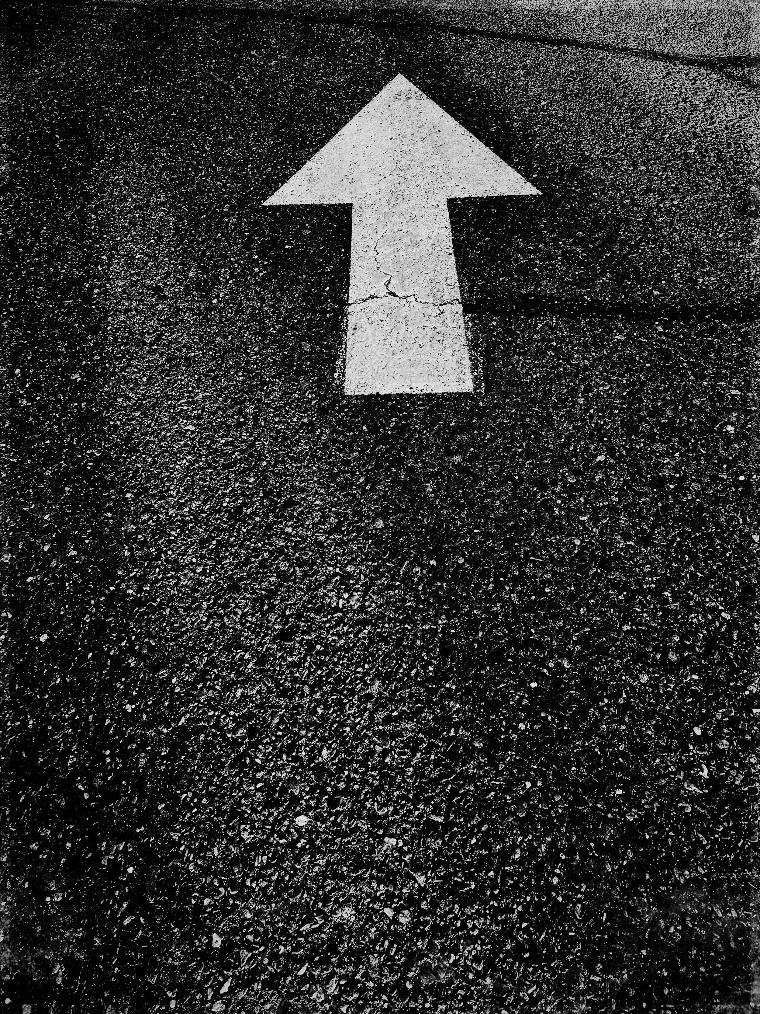 White upward arrow painted on black asphalt road surface.