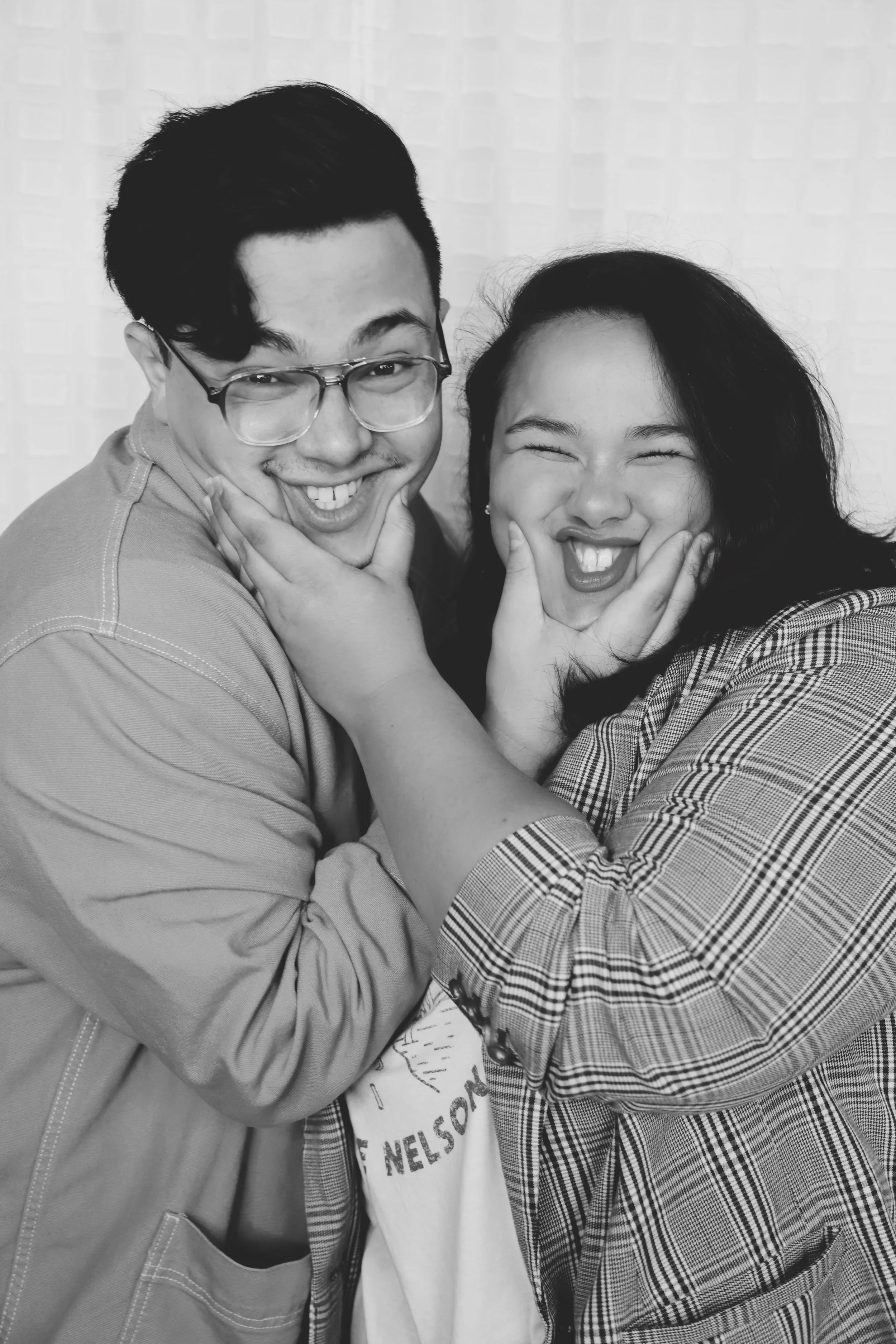 Two people smiling and playfully holding their faces while posing for the camera.
