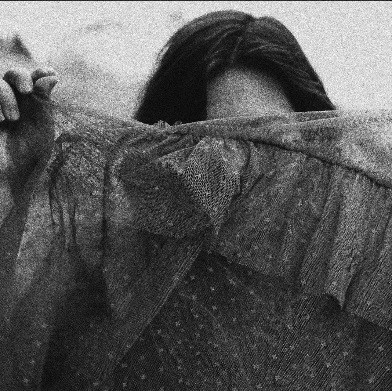 Person holding a lace curtain partially covering their face, with only their forehead and hair visible.