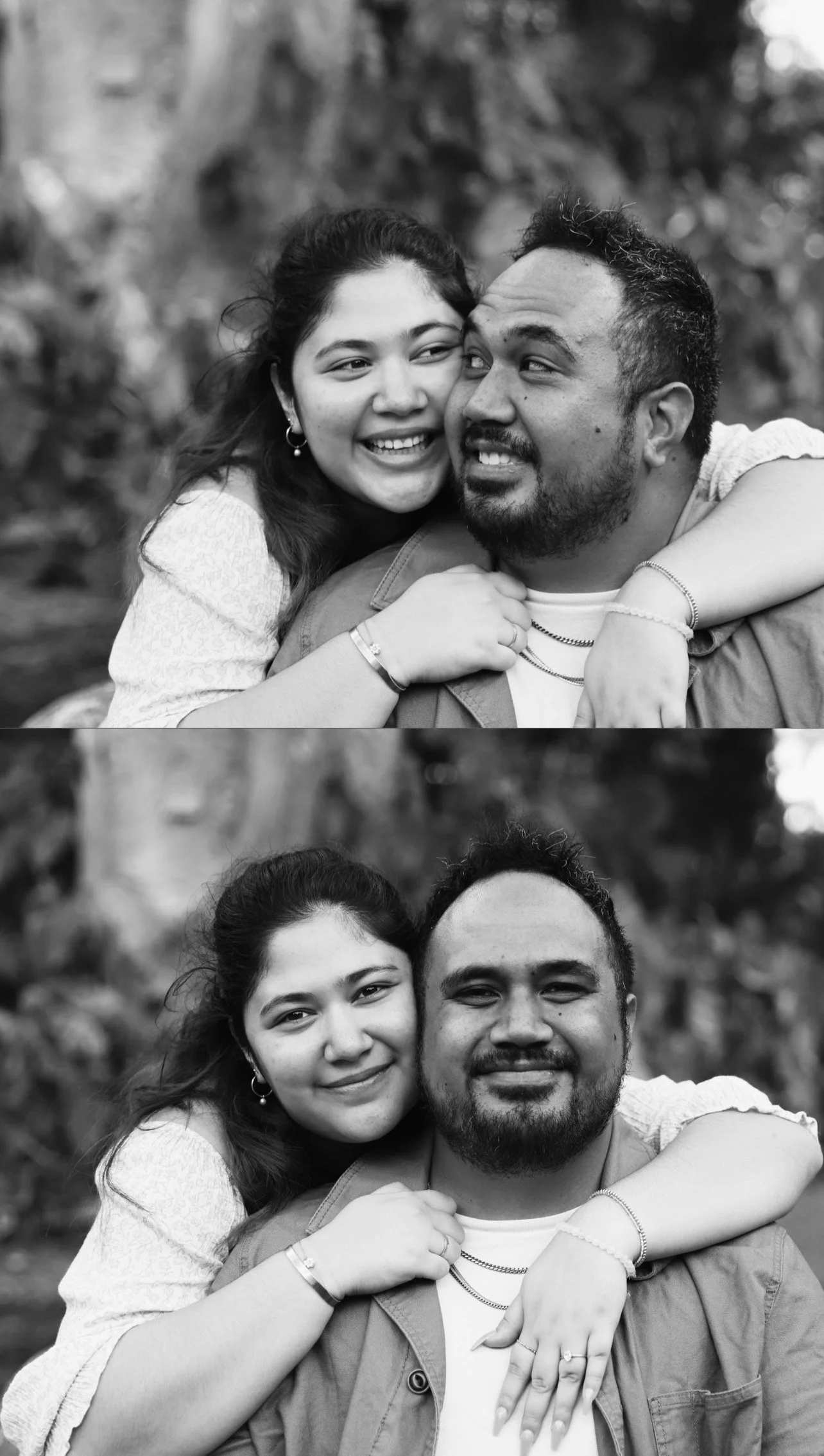 A black and white photo of a smiling couple, with the woman hugging the man from behind, both looking at the camera.