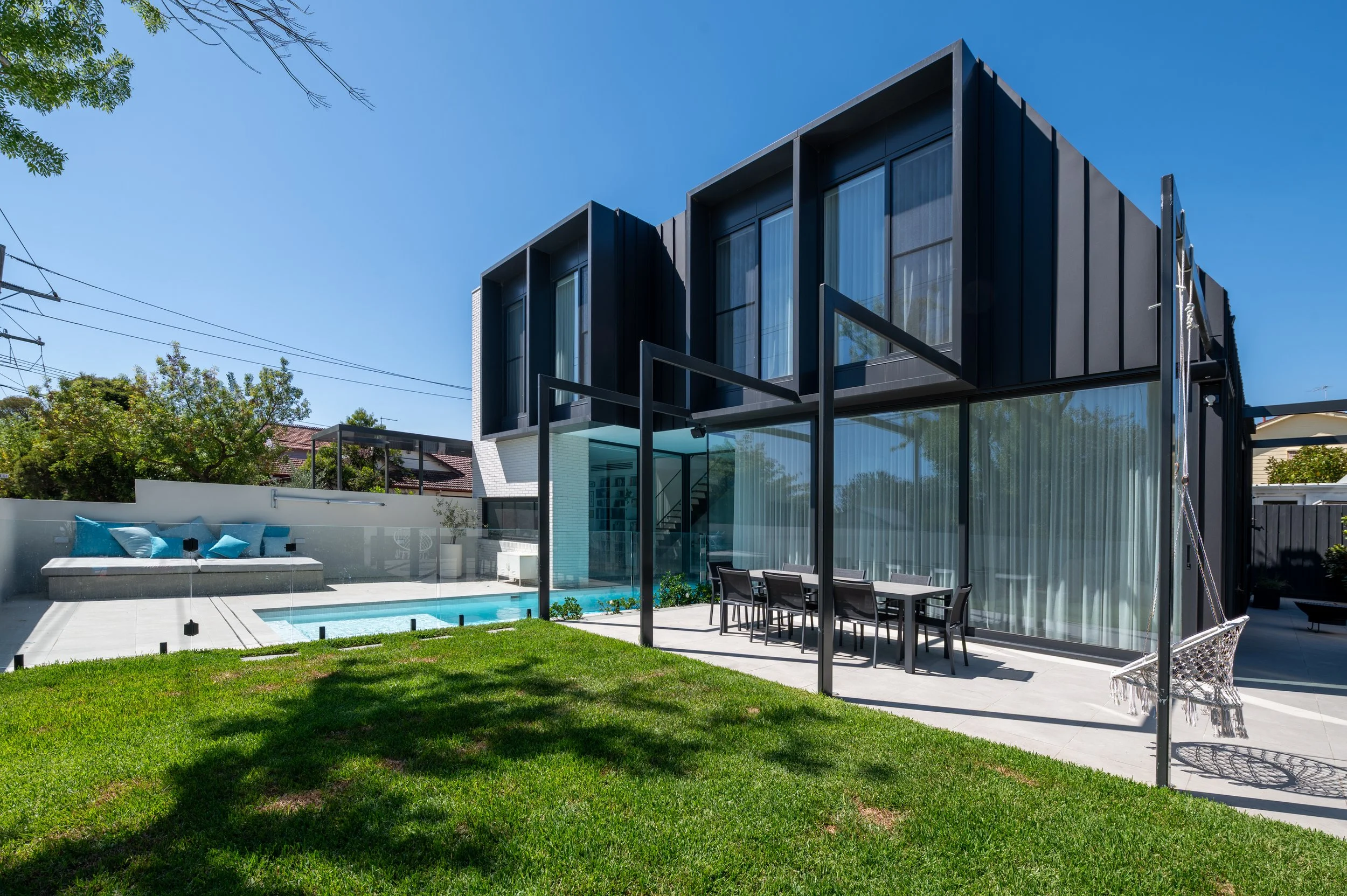 Compact Brighton backyard designed for family play and entertaining, featuring landscaped garden, pool, and bespoke lift-up pool seat concealing equipment.