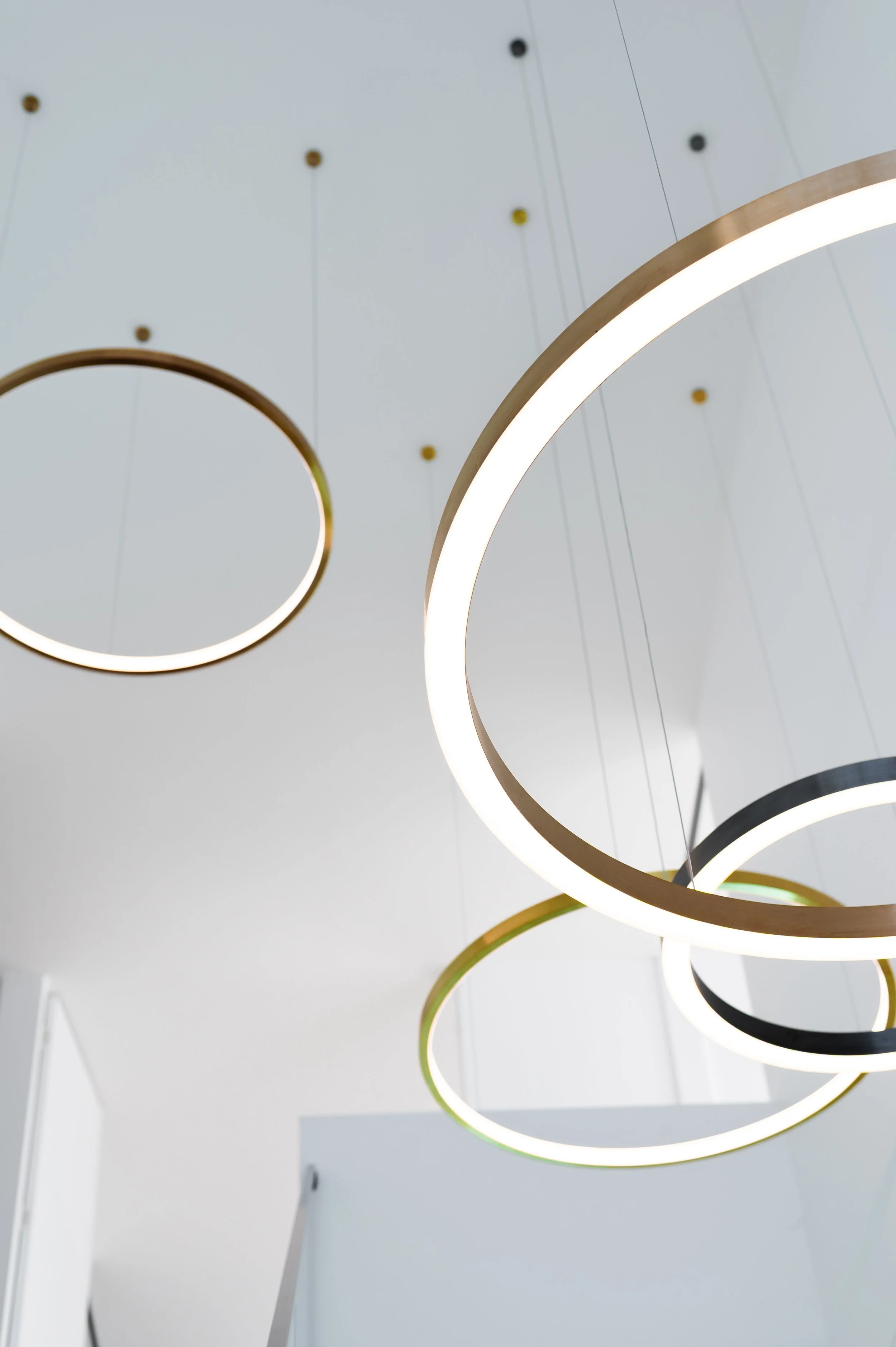 Close-up of the decorative lighting in the Brighton void, featuring rings in gold, copper, and black finishes.