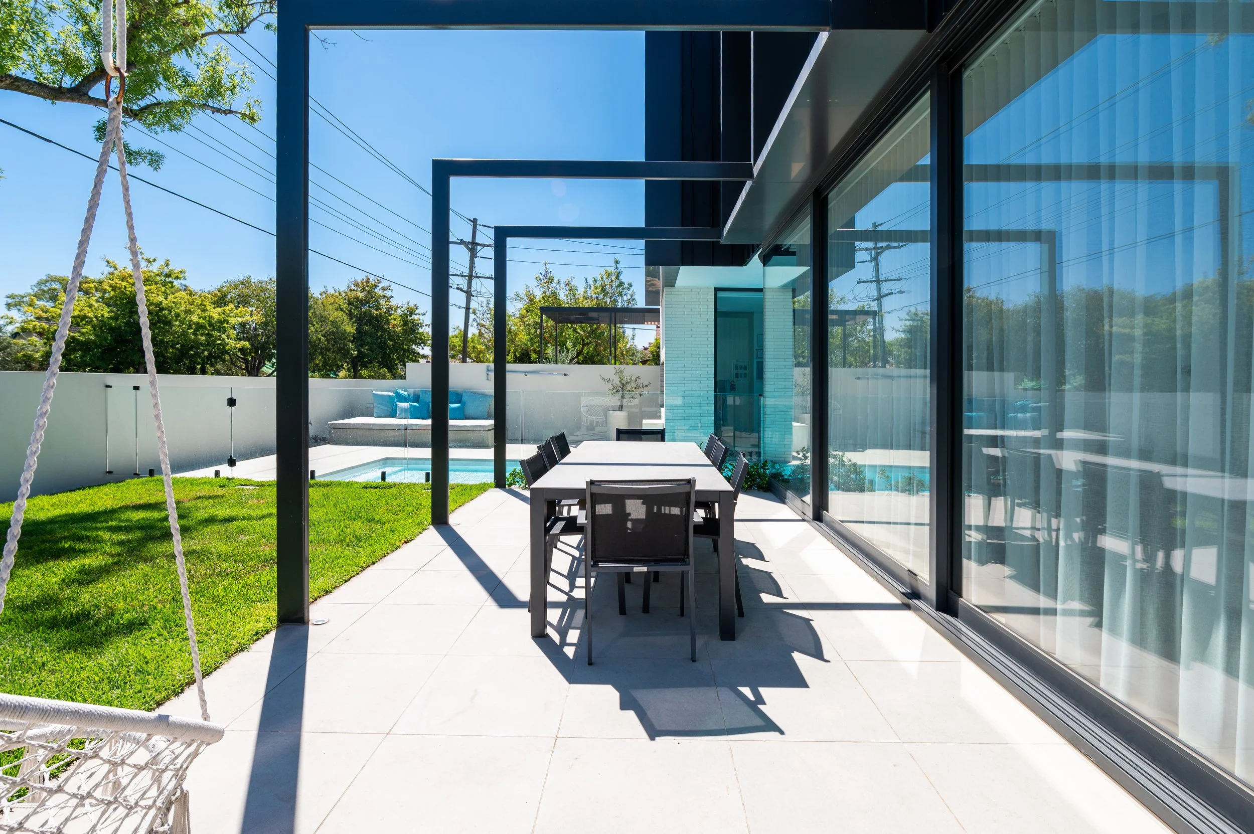 View from the Brighton outdoor entertaining and dining area towards the pool, showing seamless flow between interior and exterior spaces.