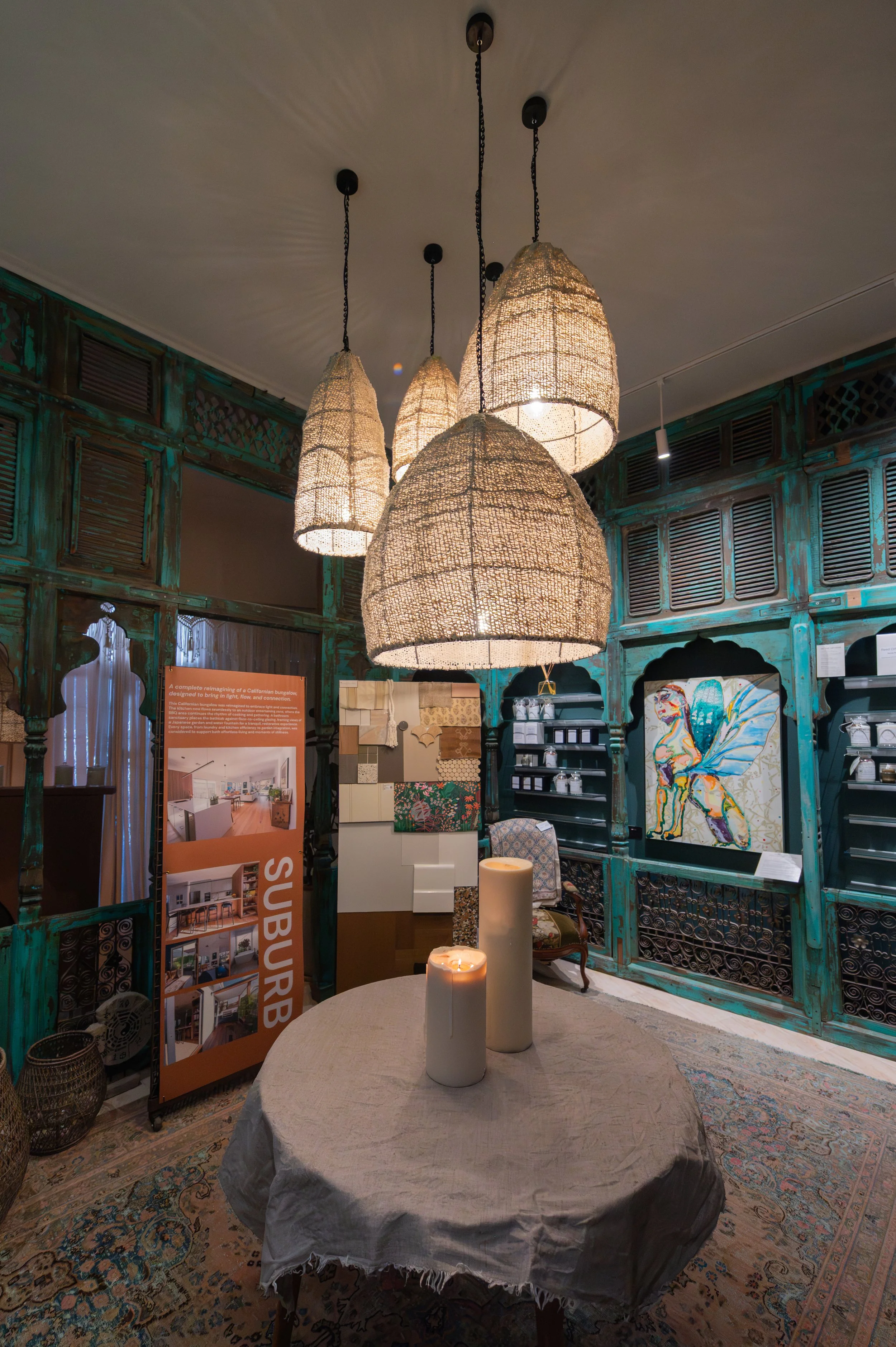 Interior of Colour Colour studio featuring a 150-year-old Indian temple, hand-knotted rug, cluster of five handmade cotton pendants, original artwork on the walls, and handmade pillar candles.