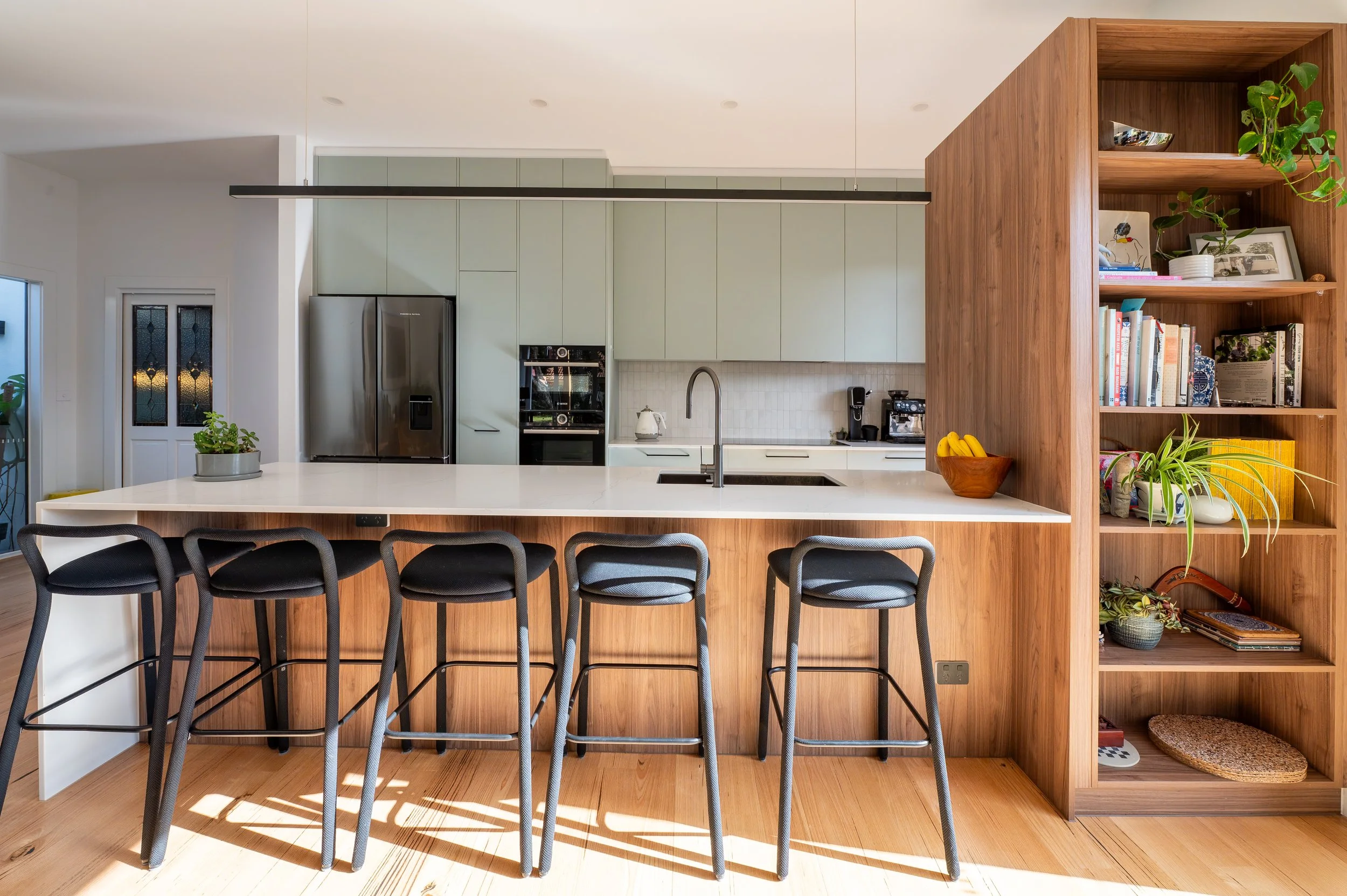 Kitchen with integrated bookcase facing the living room in a reimagined Oak Street Californian bungalow