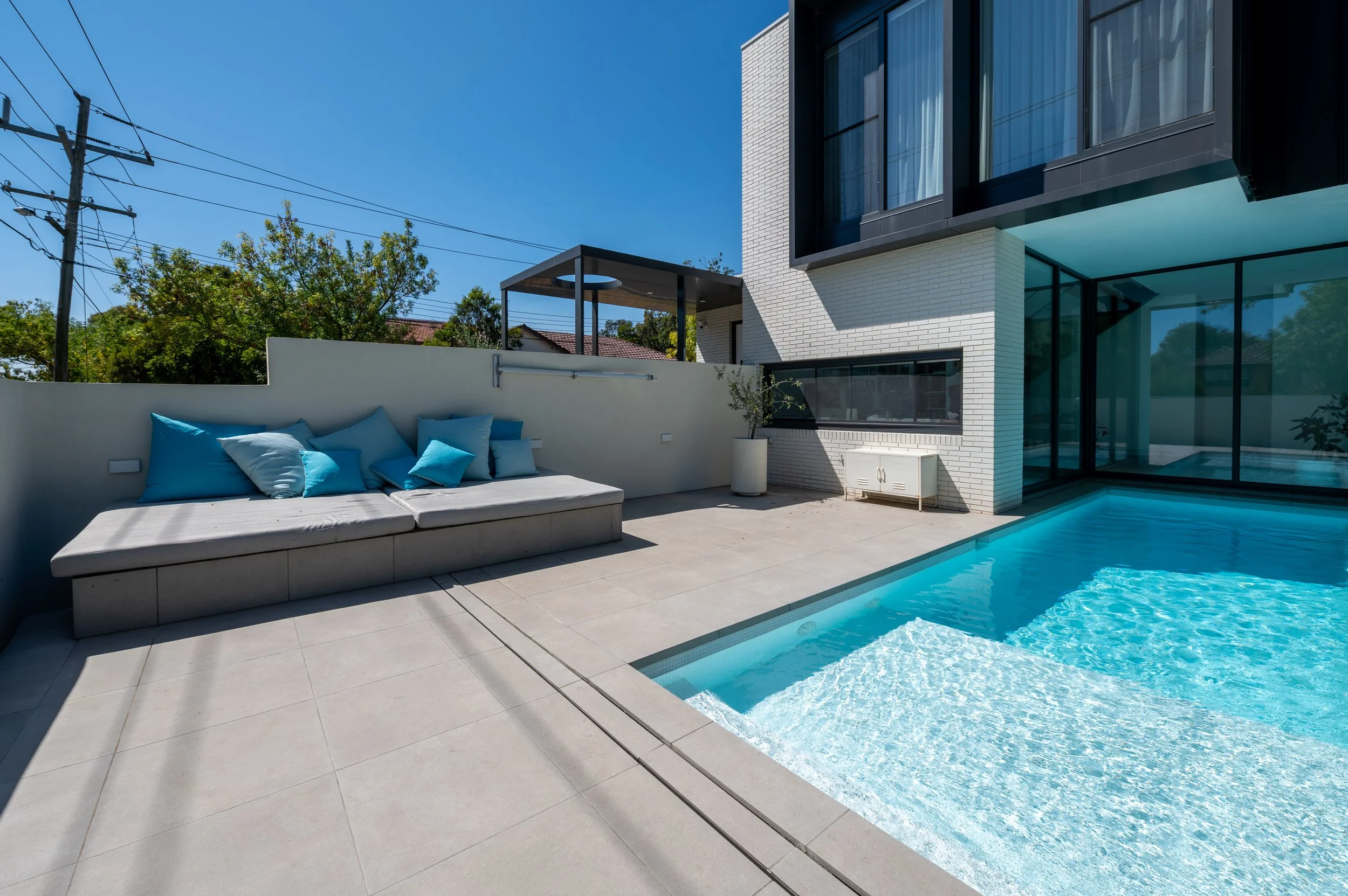 Brighton pool area showing landscaped surroundings and the custom lift-up pool seat concealing equipment for a clean, functional design.