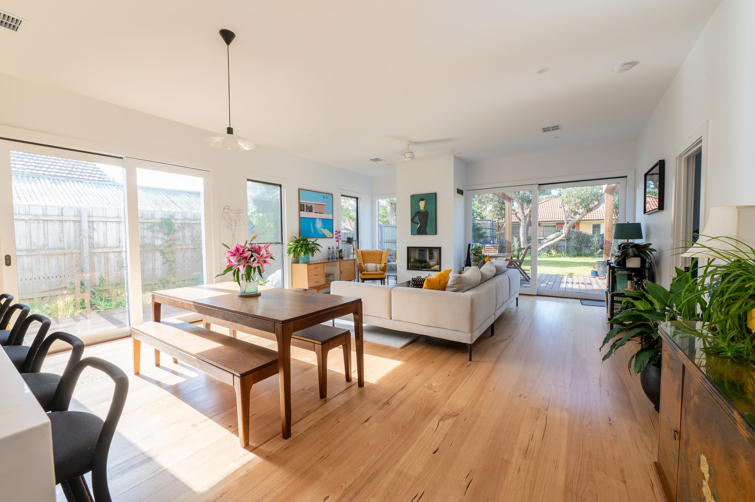 Oak Street Project open-plan lounge and dining area, featuring the fireplace, clients’ existing furniture and artwork, and a seamless connection to the backyard, with the space designed around the items the family wanted to keep.