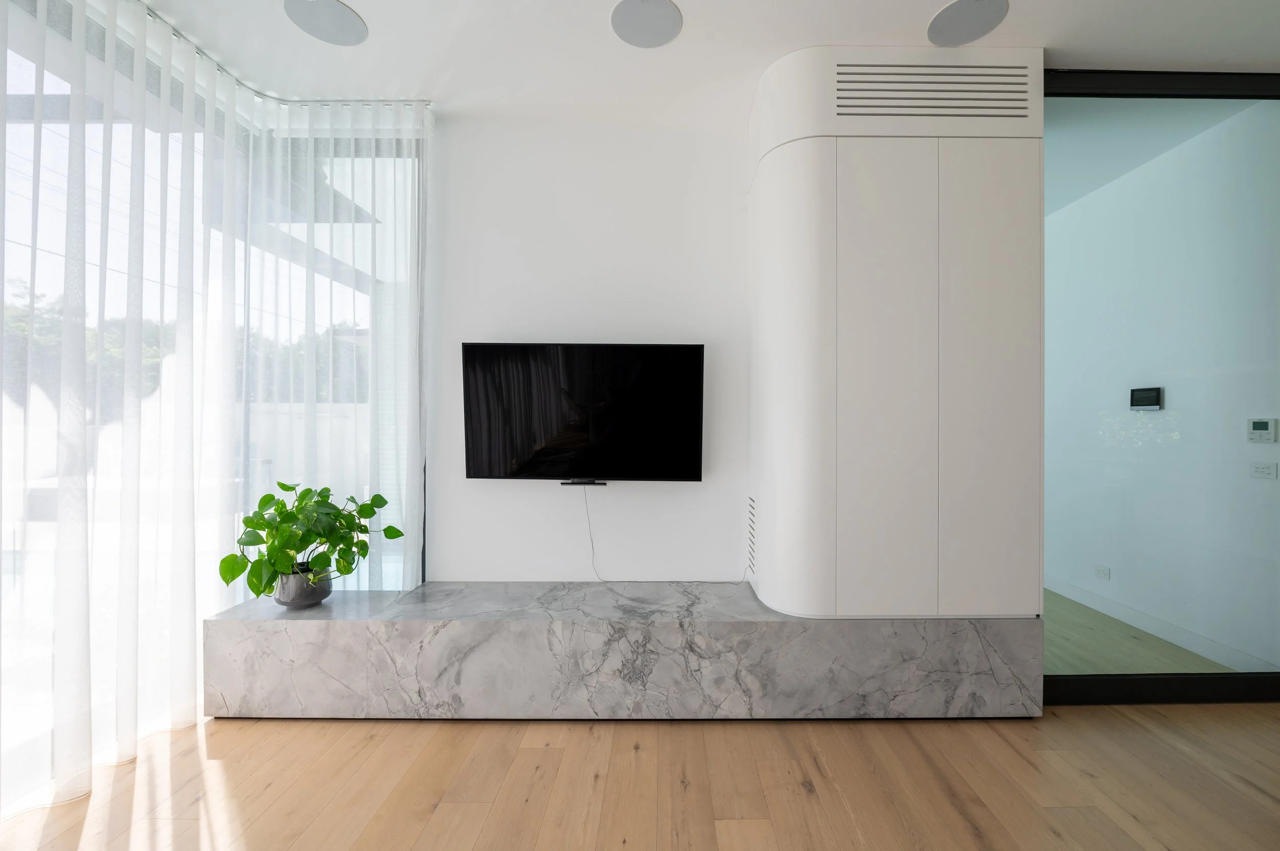 Brighton entertainment unit with a custom curved cupboard, designed to house TV equipment, subwoofer, and storage, softening the straight lines of the interior