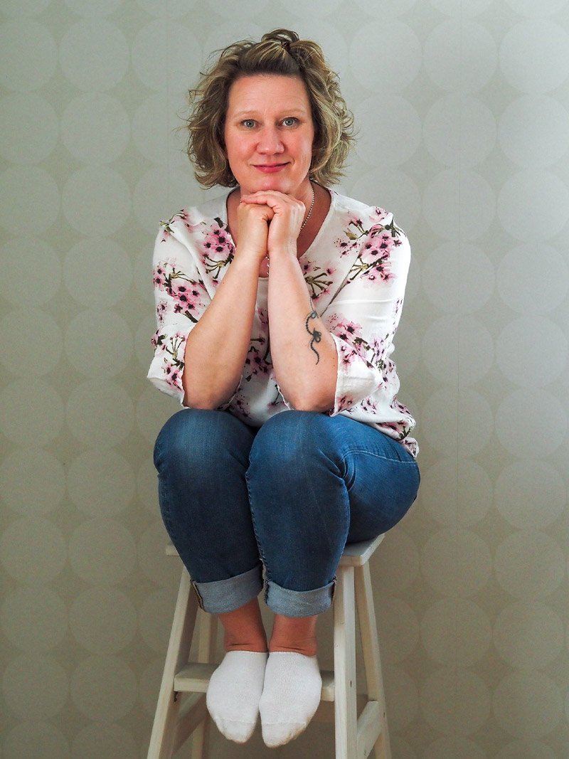 Neuropsykiatrinen valmentaja Mia Pyykkö istuu jakkaralla ja nojaa käsillä leukaansa.