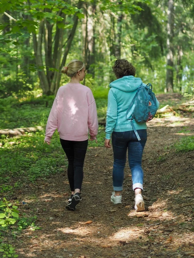 Toimintaterapeutti Mia Pyykkö asiakkaansa kanssa kävelyllä metsäpolulla.