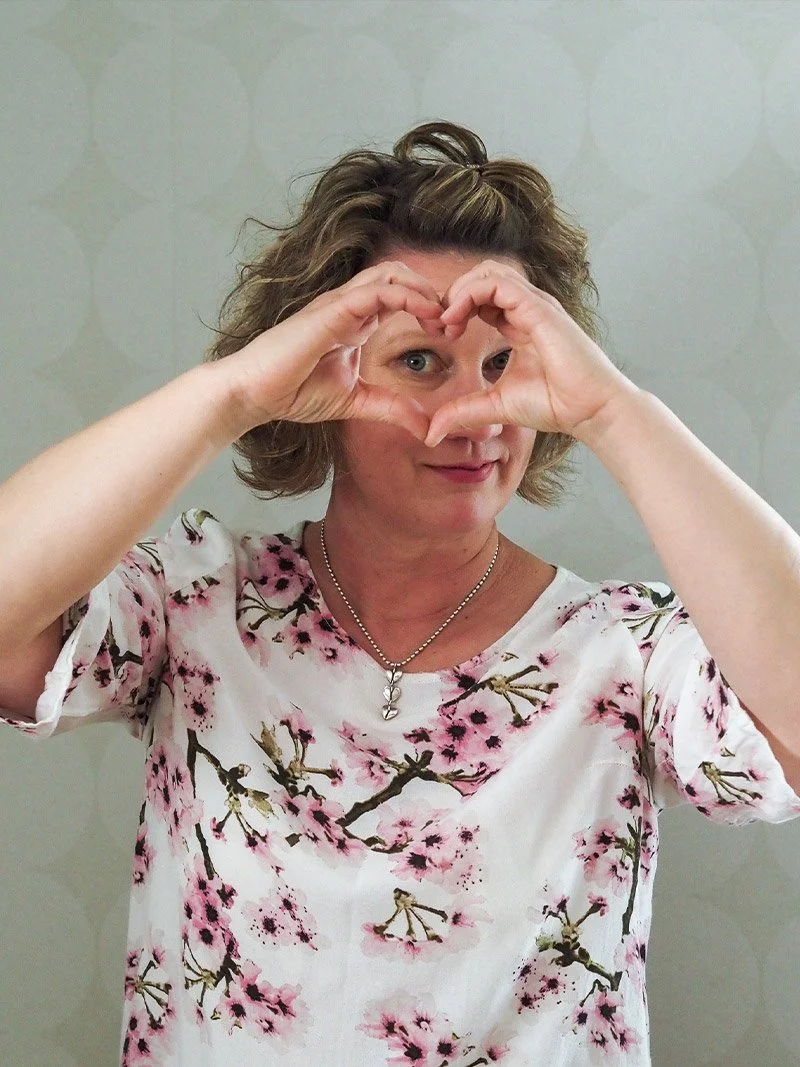 Mia Pyykkö hymyilee ja tekee sydämen muodon sormillaan kasvojensa edessä.