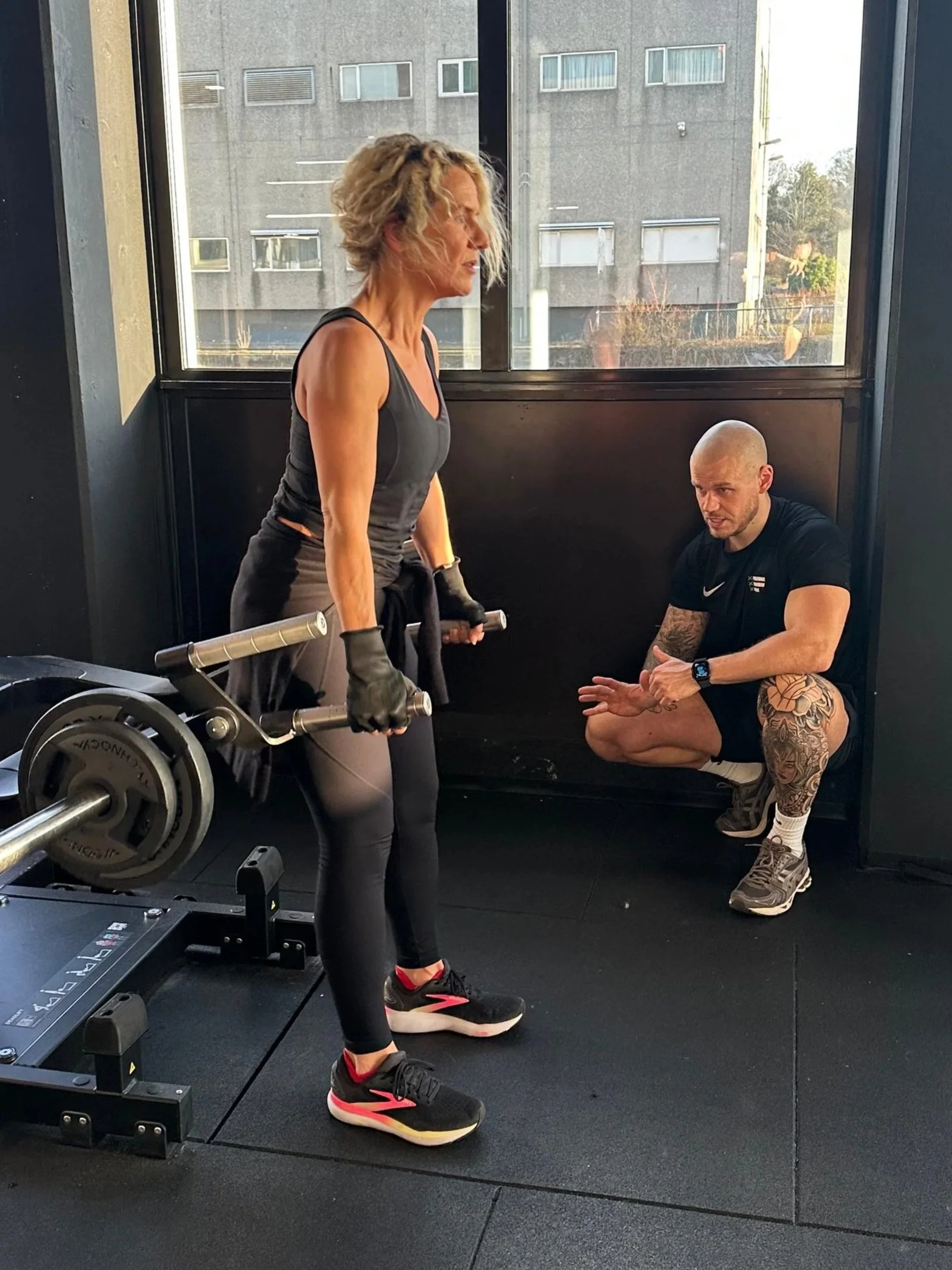 cliënt traint met gewichten onder begeleiding van personal coach