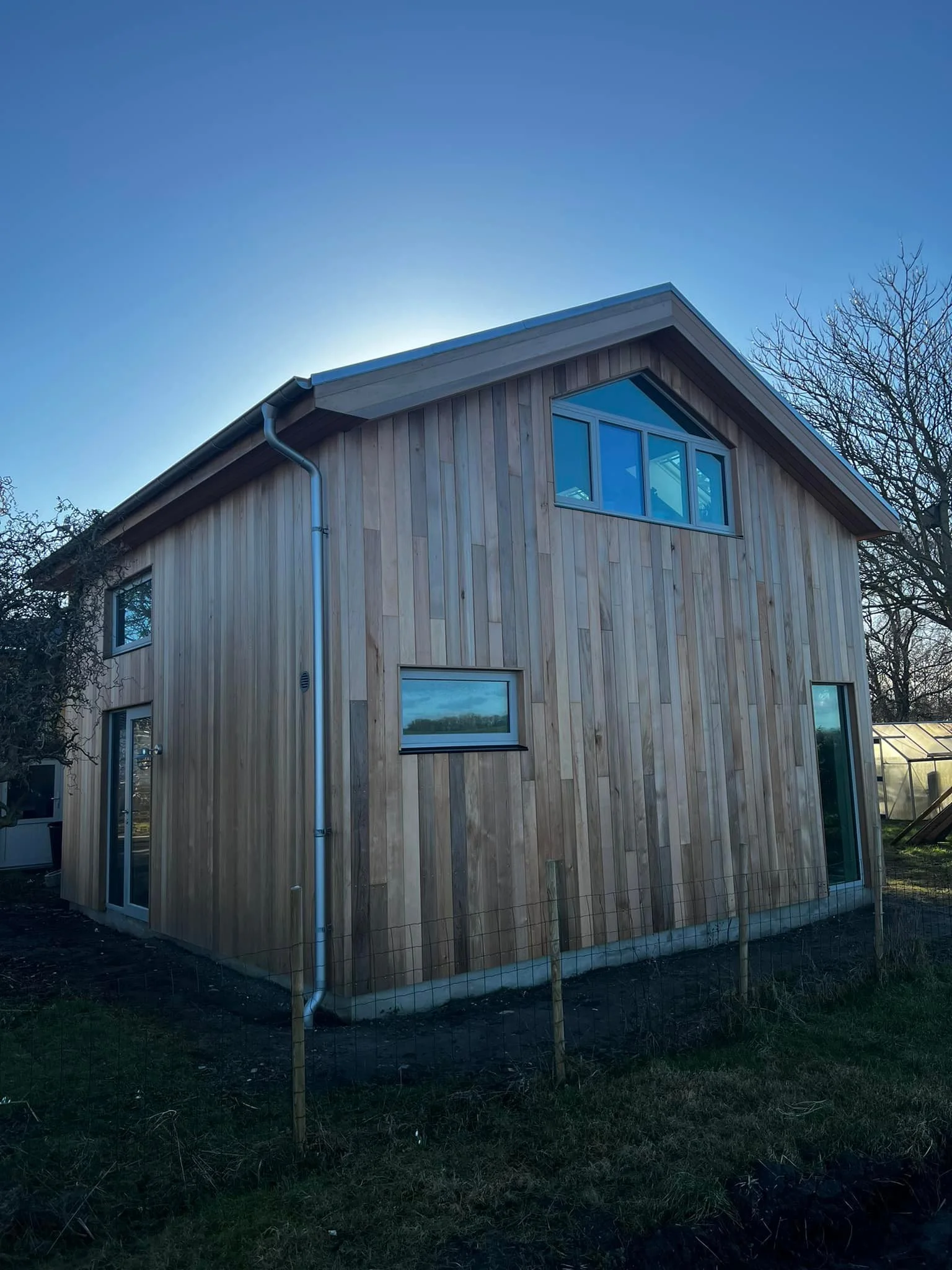 Et moderne hus med træfacade set mod eftermiddags- eller aftenhimmel.