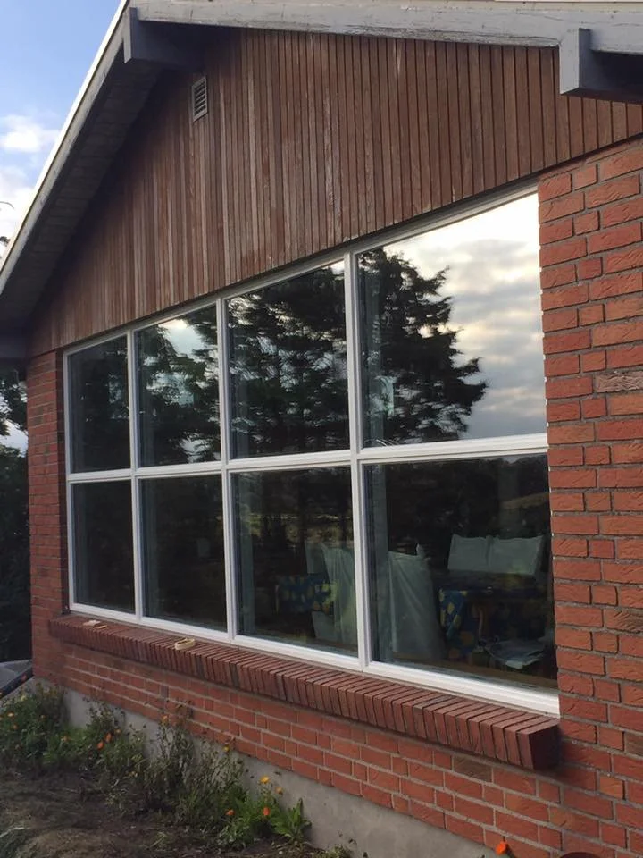 Et vindue med seks ruder på en murstensvæg med træbeklædning øverst.