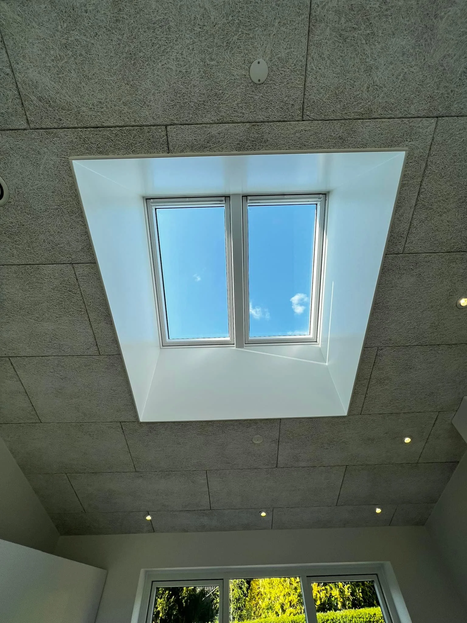 Hvælving med ovenlys vindue der viser blå himmel og skyer.