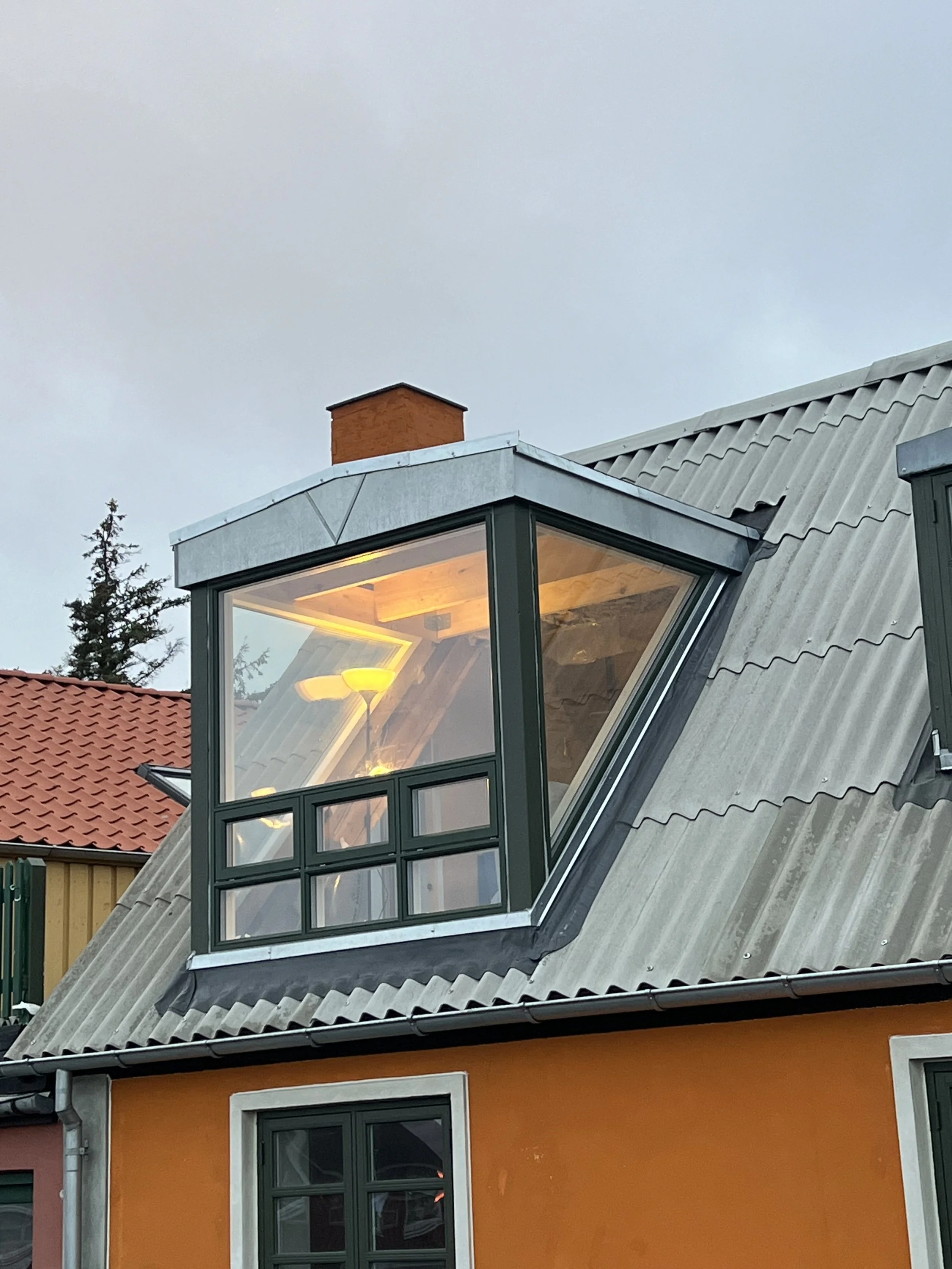 En moderne bolig med et hævet vindue på taget, hvor der er lys indendørs.