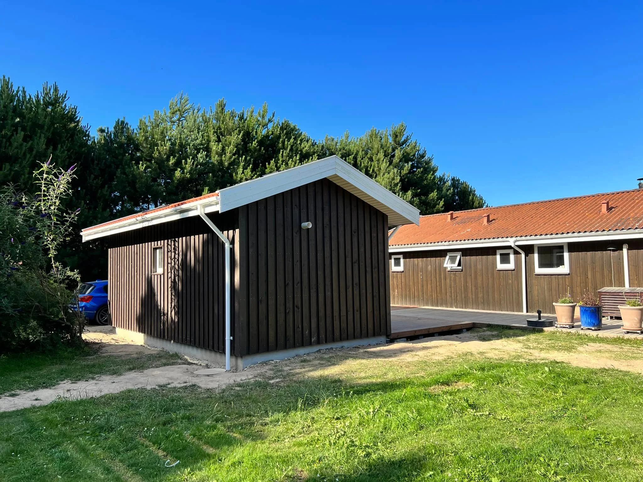 Hvide og sorte hytter med rød tegltag i en grøn have under en klar blå himmel.