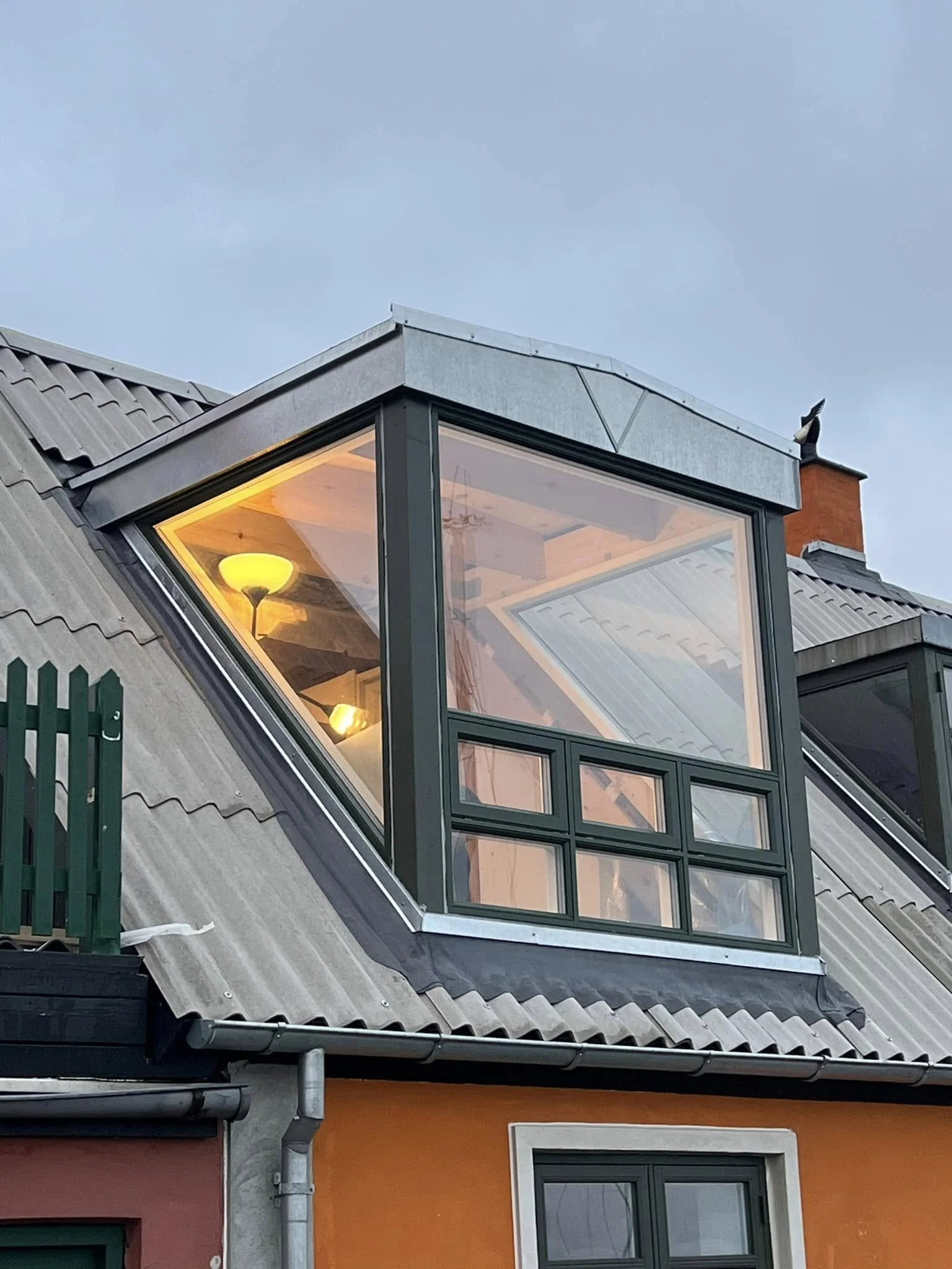 Et malinget hus med et tilføjet kvadratisk og trekantet vindue, der sidder på taget.