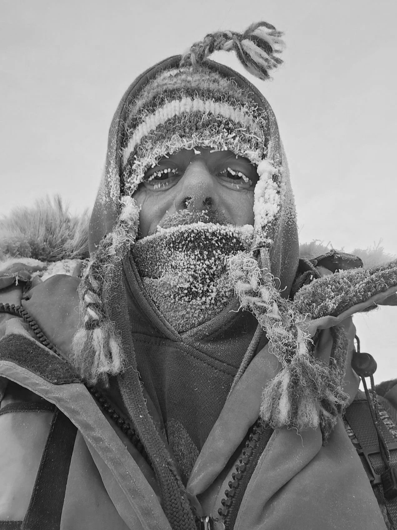Homme en vêtements d'hiver dans un environnement enneigé, face à la caméra.