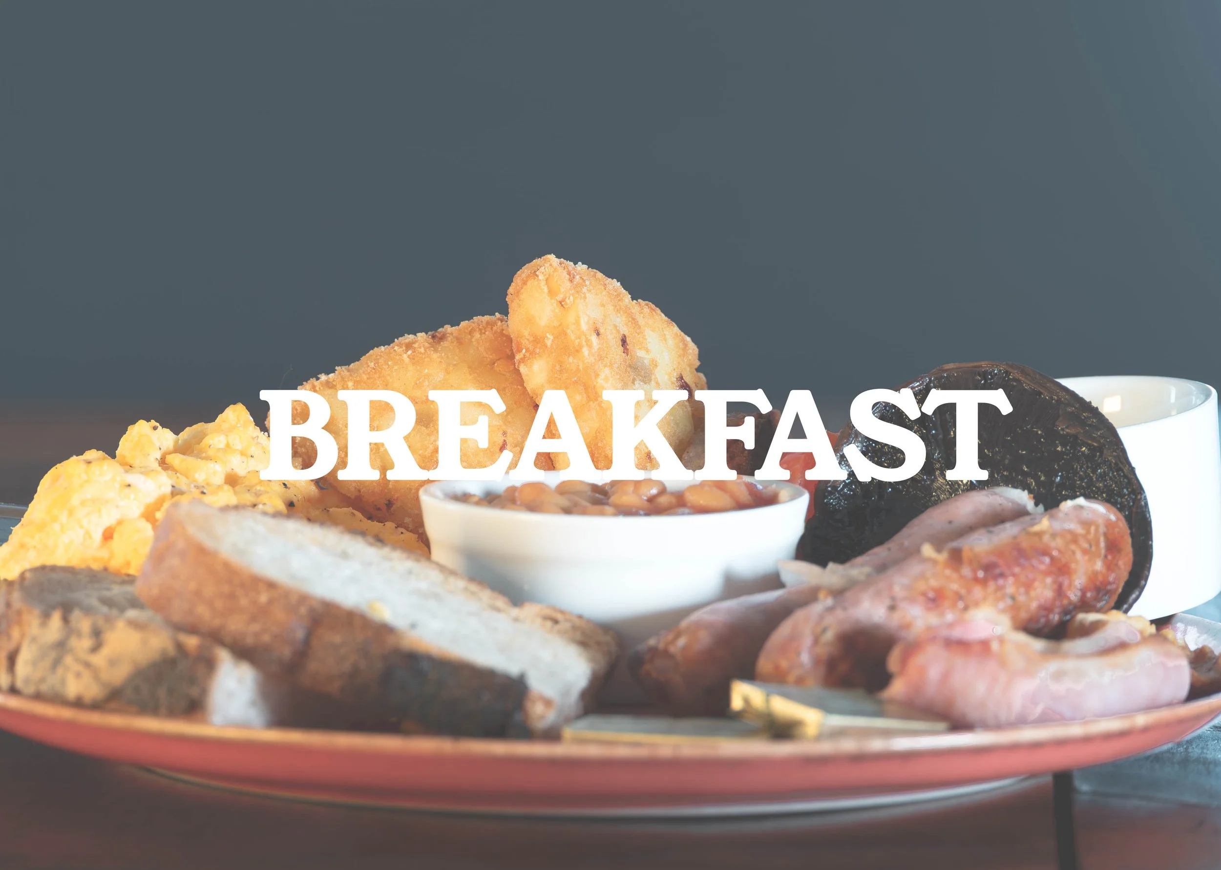 A breakfast plate with various items including fried potatoes, scrambled eggs, toast, baked beans, bacon, sausage, and an English muffin, with the word 'BREAKFAST' overlaid in white text.