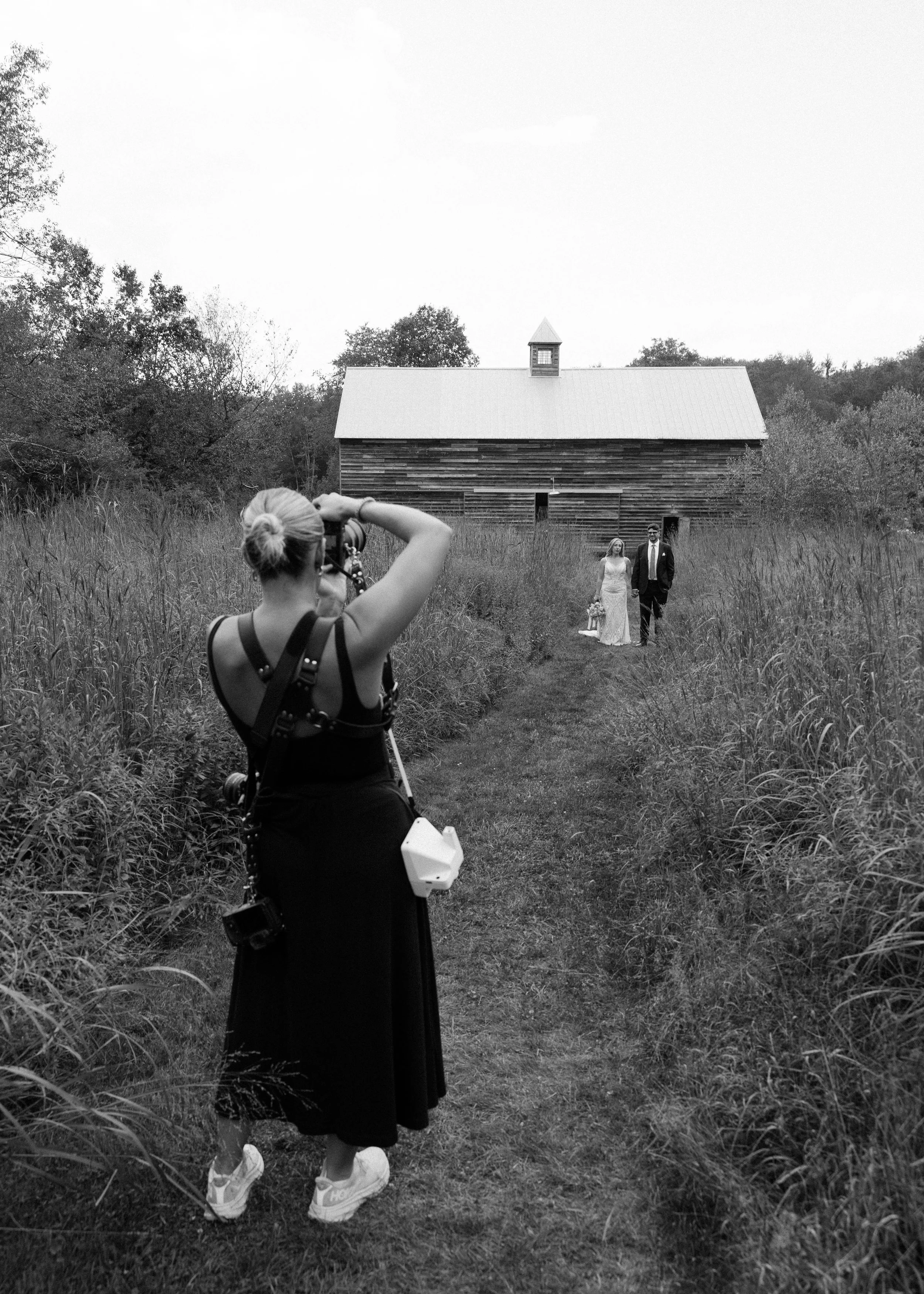 Documentary-style black and white wedding photography showing a photographer at work capturing a couple at Handsome Hollow in Beacon, NY.