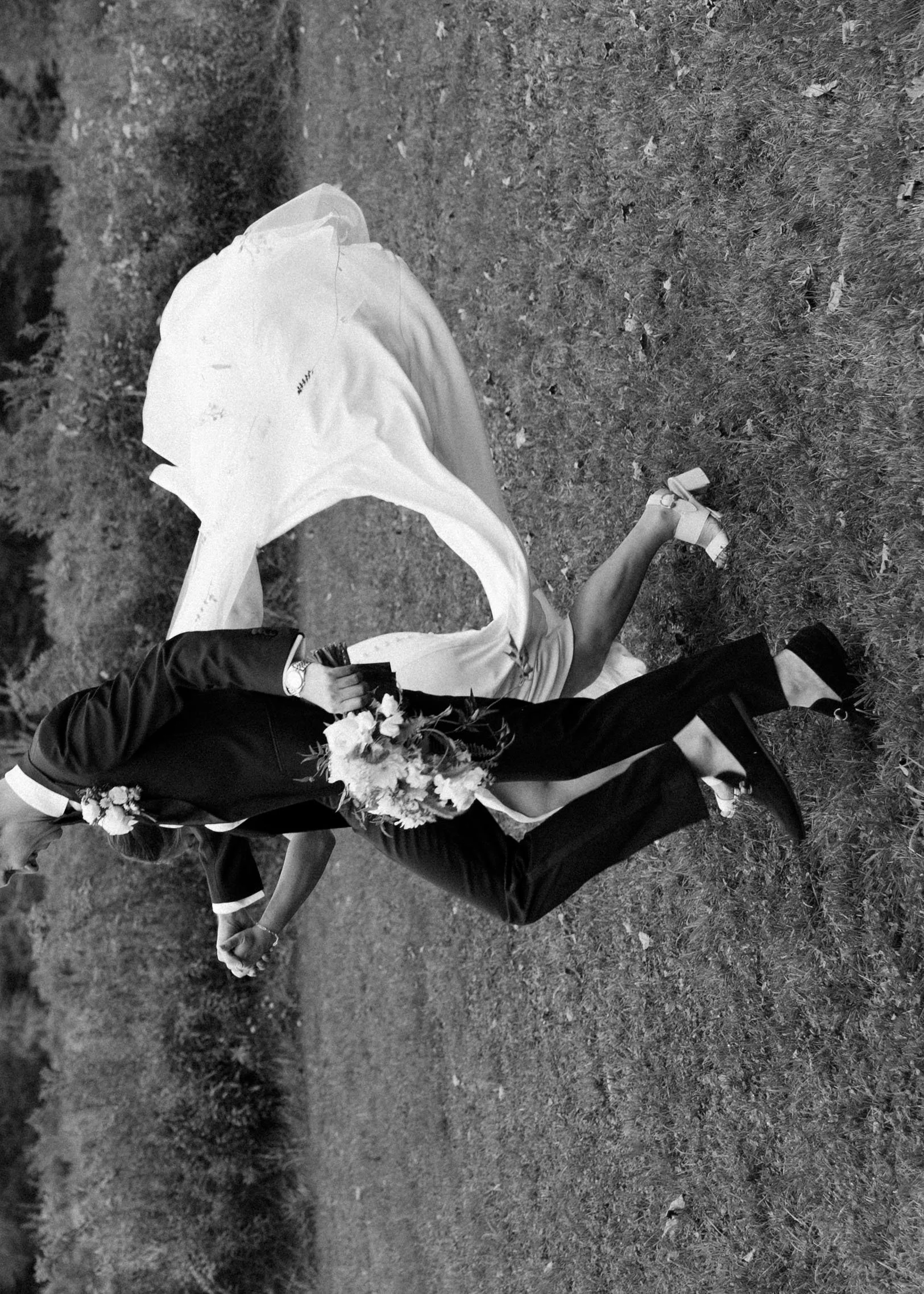 Black and white documentary wedding photo of a bride and groom running hand in hand at Handsome Hollow.