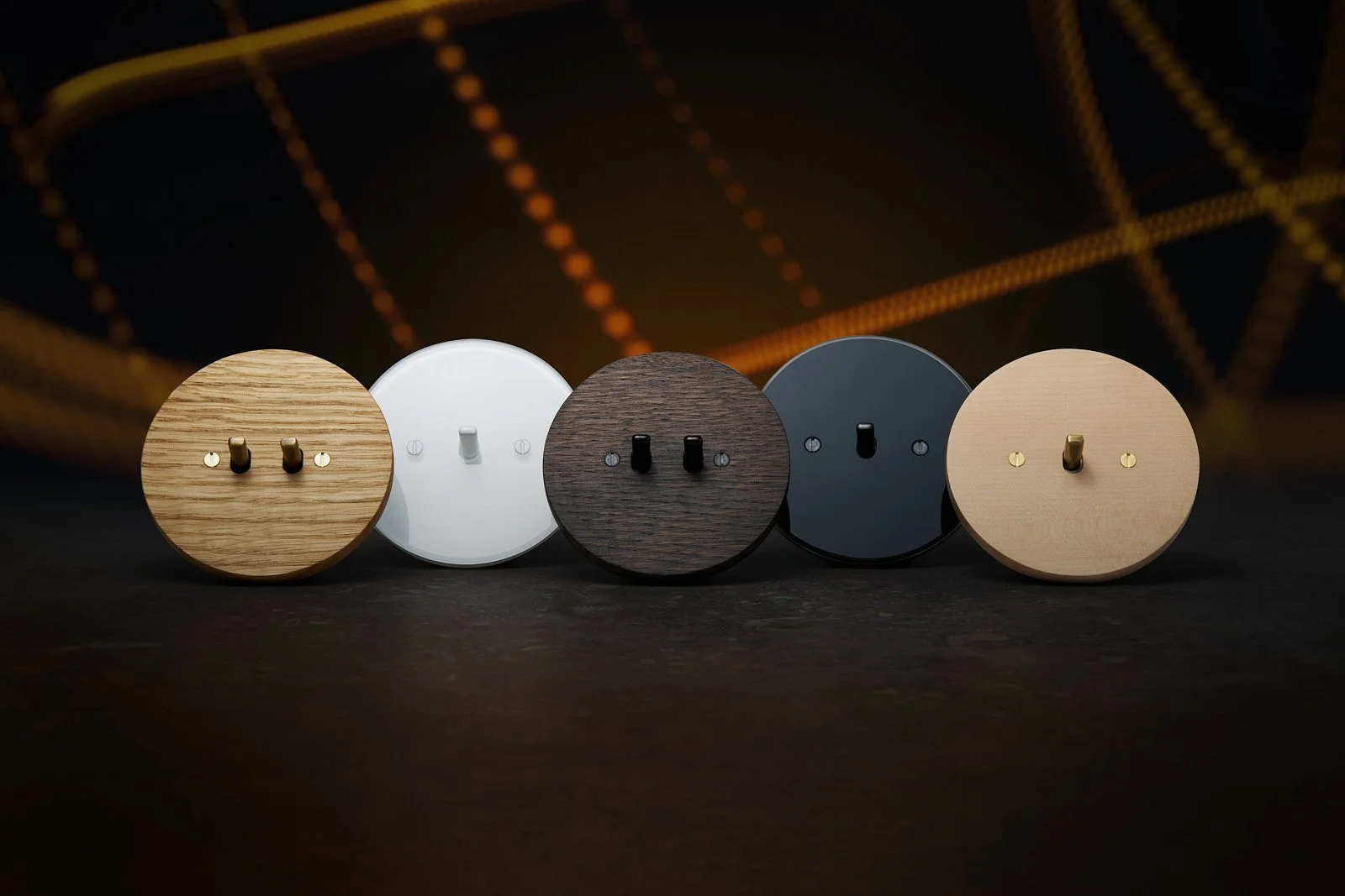 Five round wooden and plastic wall hooks with hooks in different colors and finishes lined up on a dark surface.