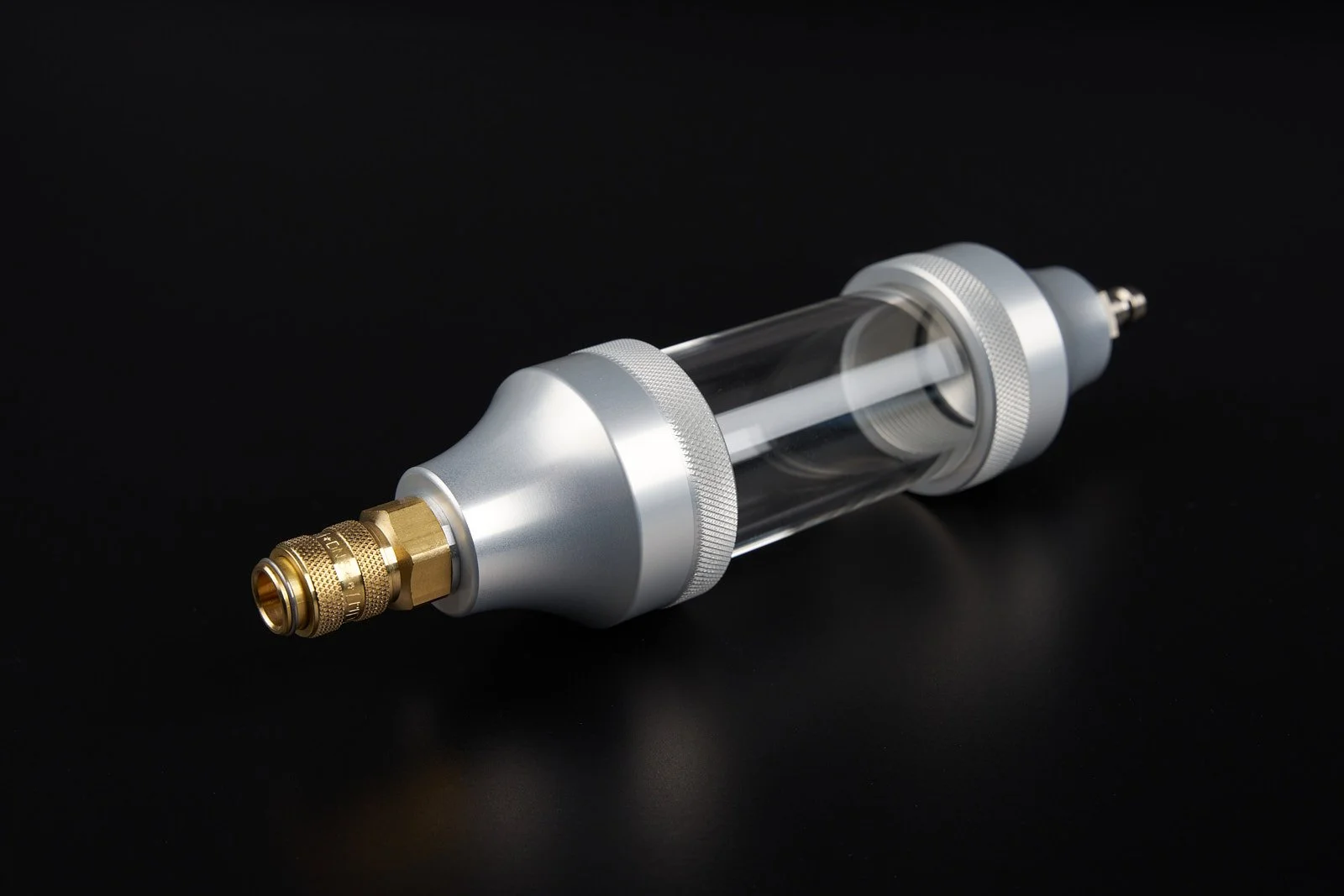 A laboratory device with a metallic and transparent glass cylindrical body, gold and silver components, and a black background.