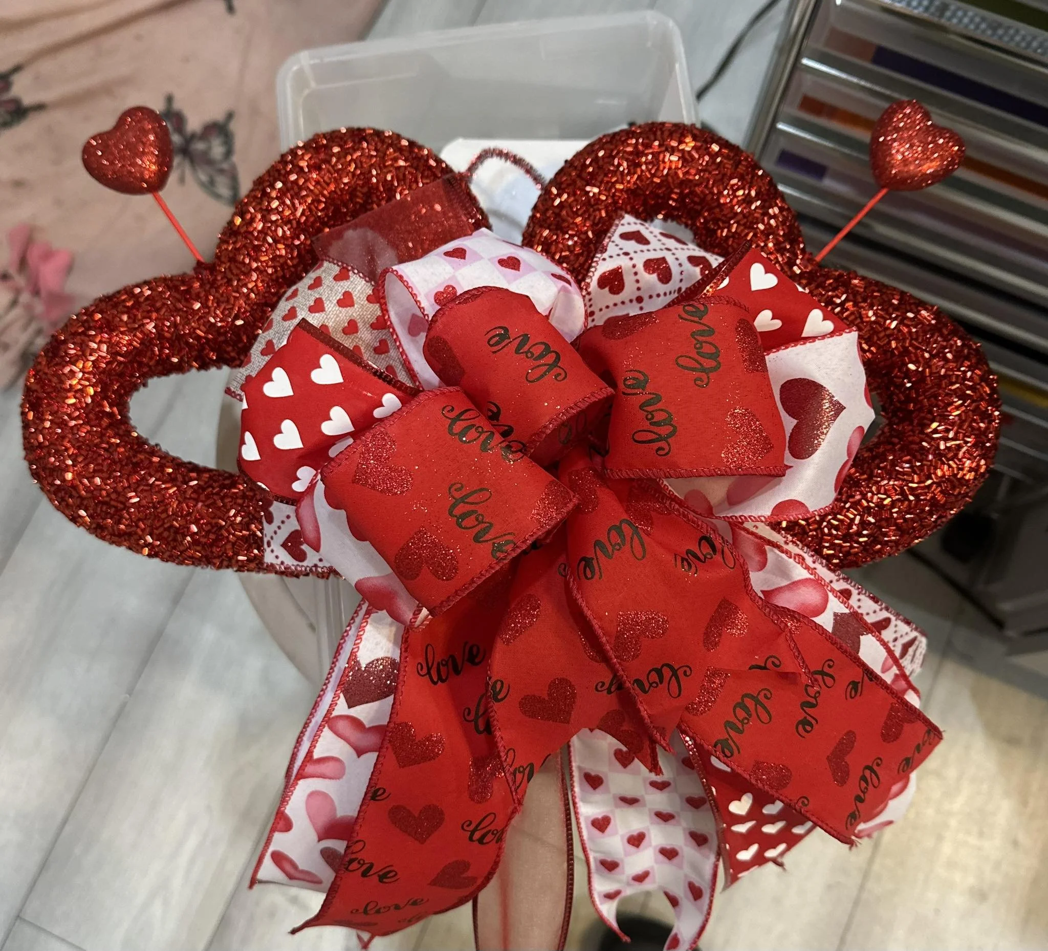 Valentine's Day bouquet with red glittery heart-shaped wreath, red and white ribbons, and heart decorations.