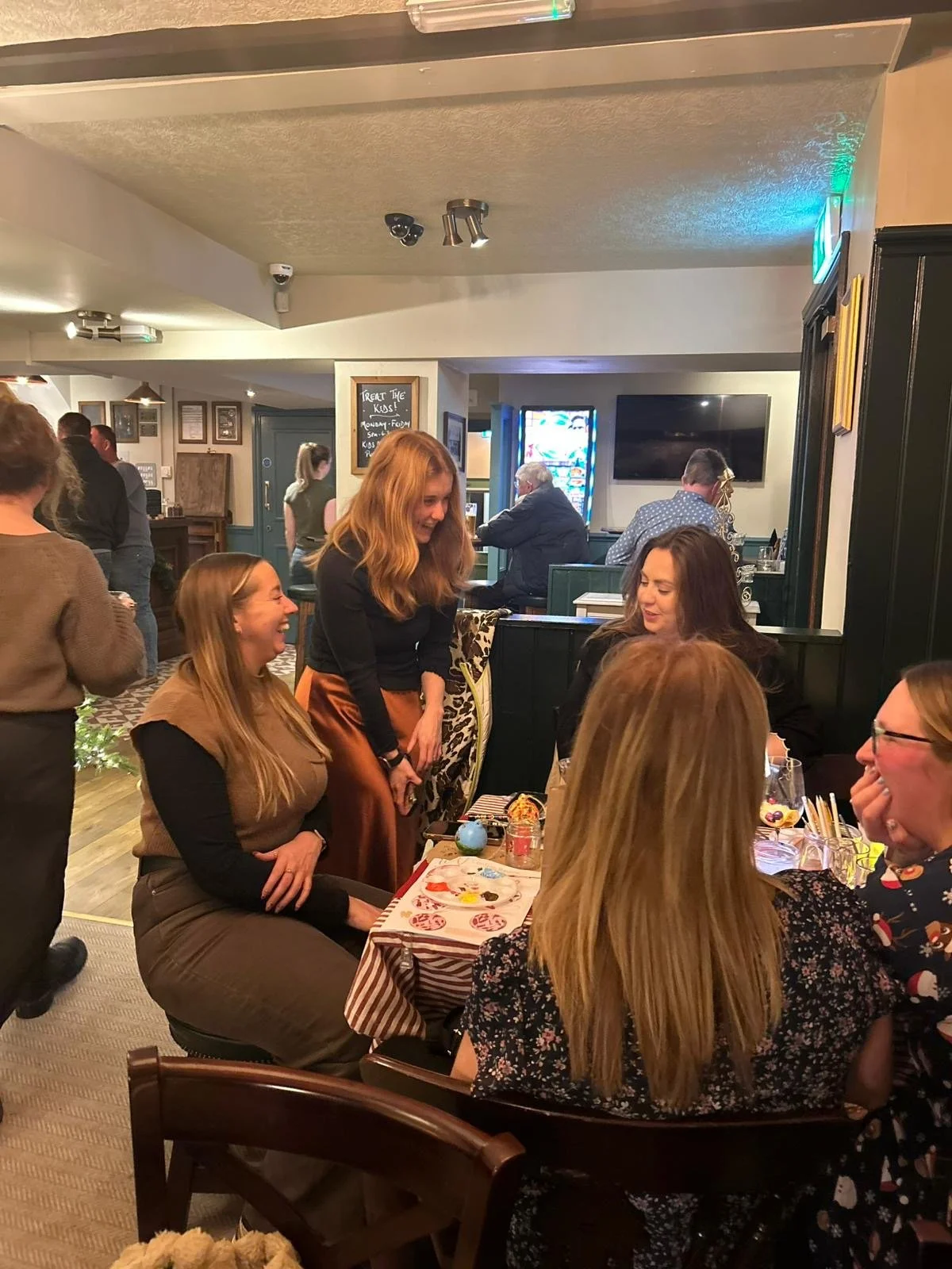 By Minutes Illustration at a social event, hosting a bauble painting workshop to a group of people at Christmas. Everyone is laughing and having a great time.