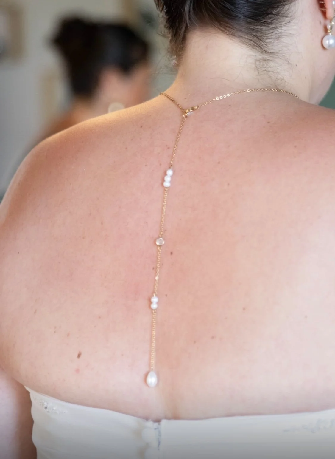 Collier en or orné de perles, porté dans le dos d'une femme