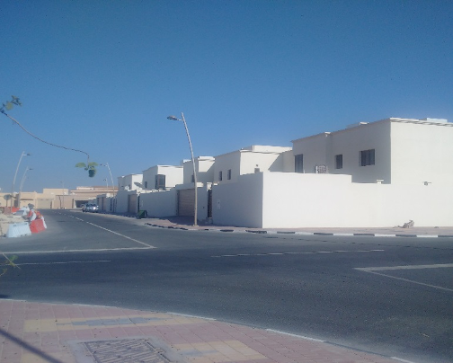 Residential buildings with white walls along a street in a sunny area.