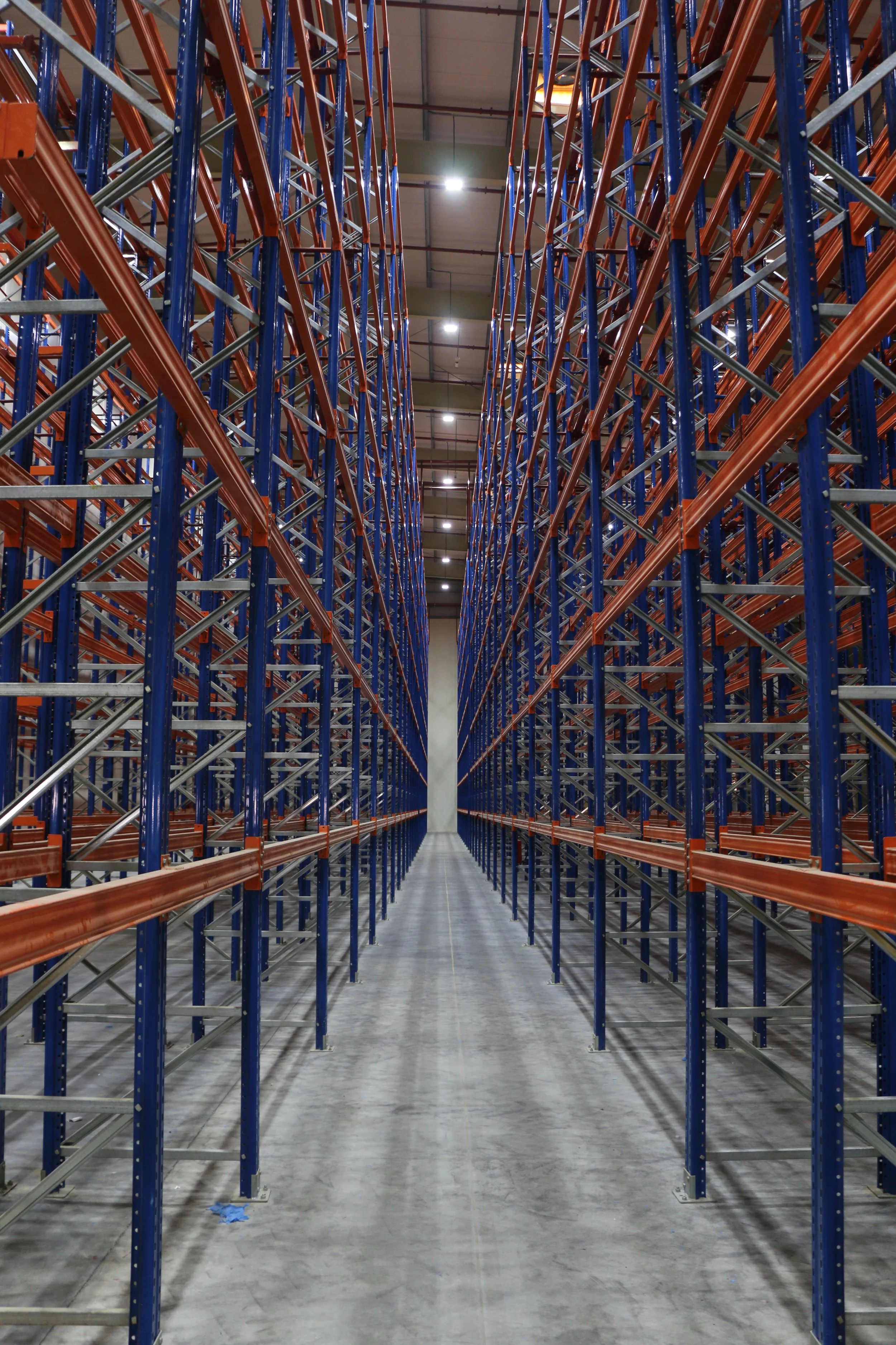 Empty warehouse with tall metal shelving units and a wide aisle.