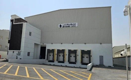 Four loading docks at a warehouse with yellow-striped parking area in front.
