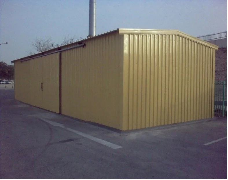 A yellow metal storage shed with a sliding door, situated in a parking lot.