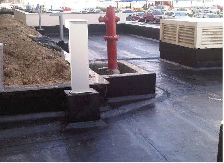 A parking lot rooftop with a red fire hydrant, a white pipe, and vent structures against a background of parked cars and buildings.