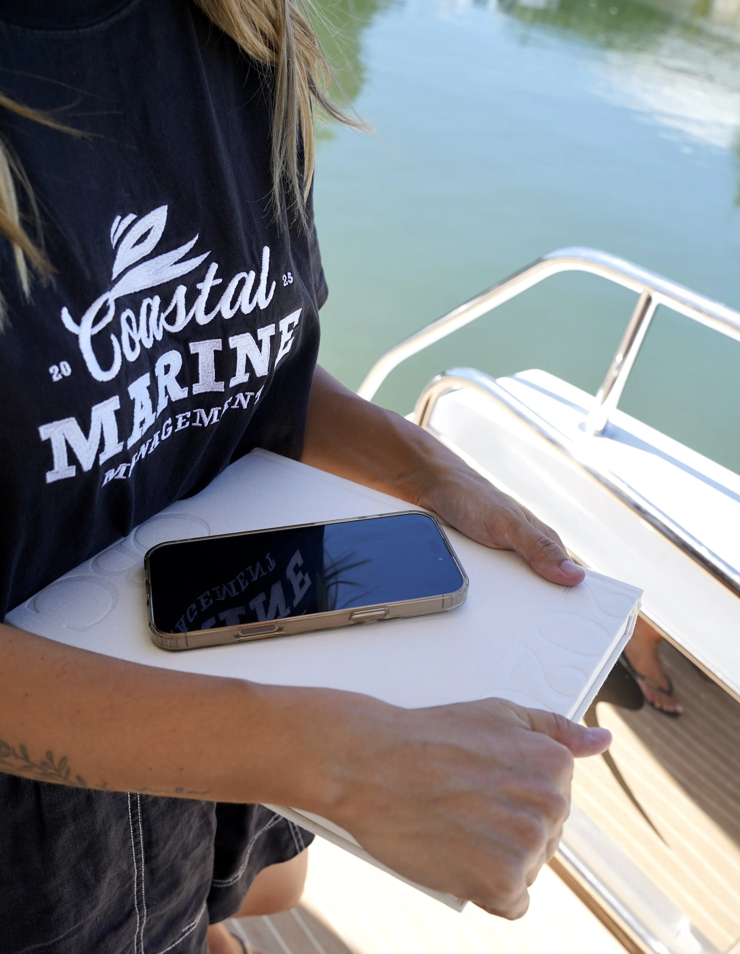 Coastal Marine Management team on a boat holding a white tray with a smartphone placed on it