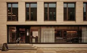 The facade of a modern building with large glass windows and a stone exterior.