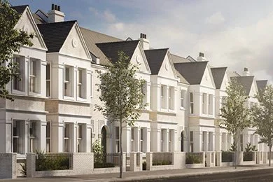 Row of modern white townhouses with front gardens and trees lining the street