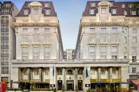 A large, historic hotel building with a grand entrance, flags, and ornate architectural details in an urban setting.