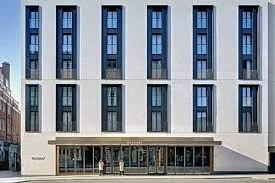 Facade of a modern multi-story building with large windows and a covered entrance
