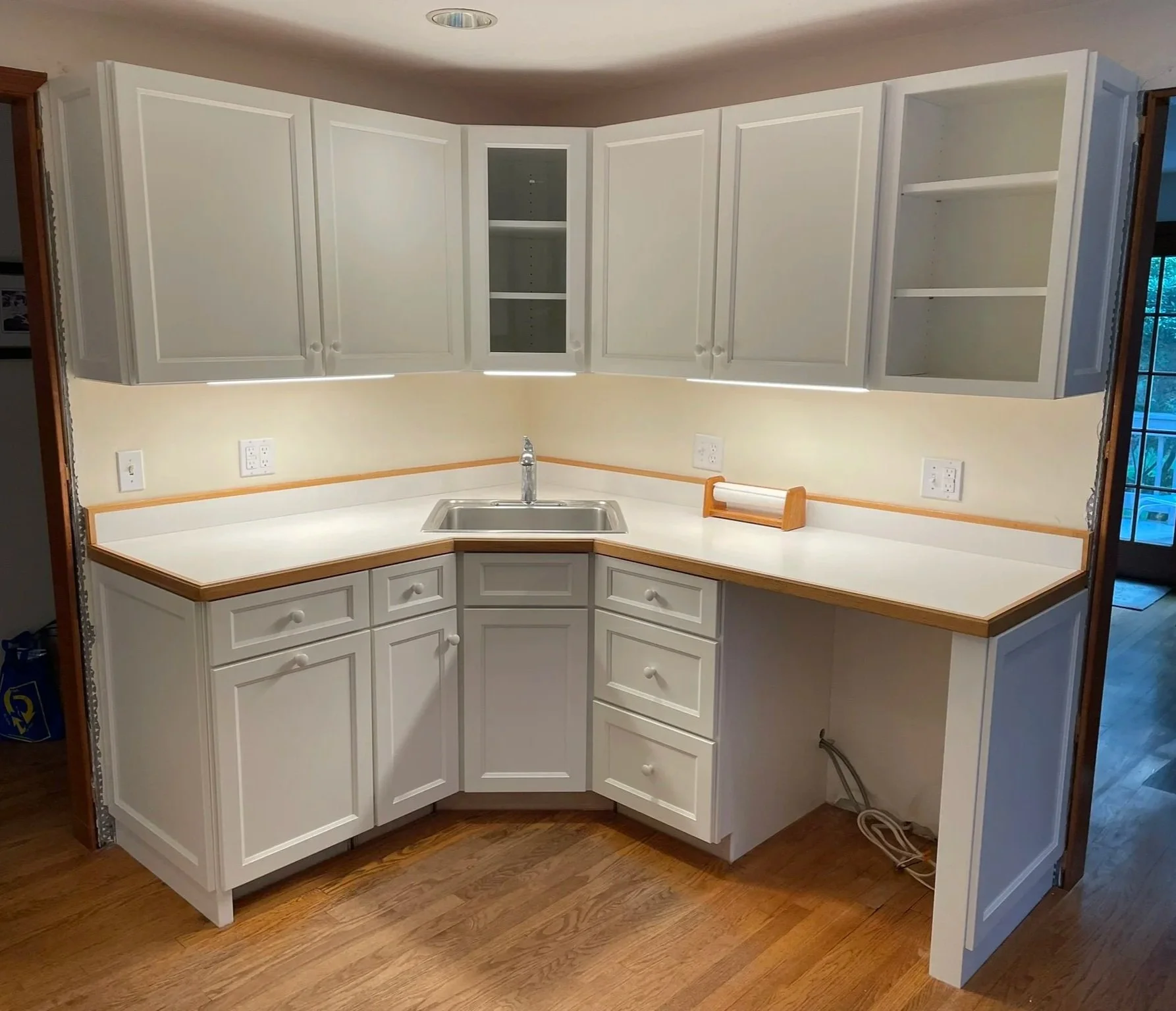 The vinyl-clad, particle board cabinets the homeowner inherited had lived a full life. Peeling vinyl and failed hinges now dominated this otherwise lovely and functional kitchen. New custom hardwood cabinets from Norfolk Kitchen and Bath were purchas