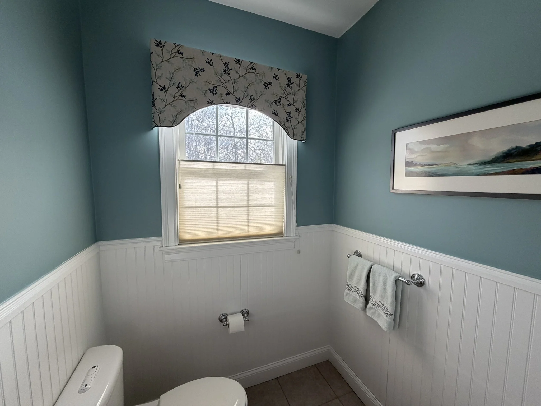 Wood wainscoting and a new wall color and window treatment brought life to a favorite waterscape painted by the homeowner's mother.