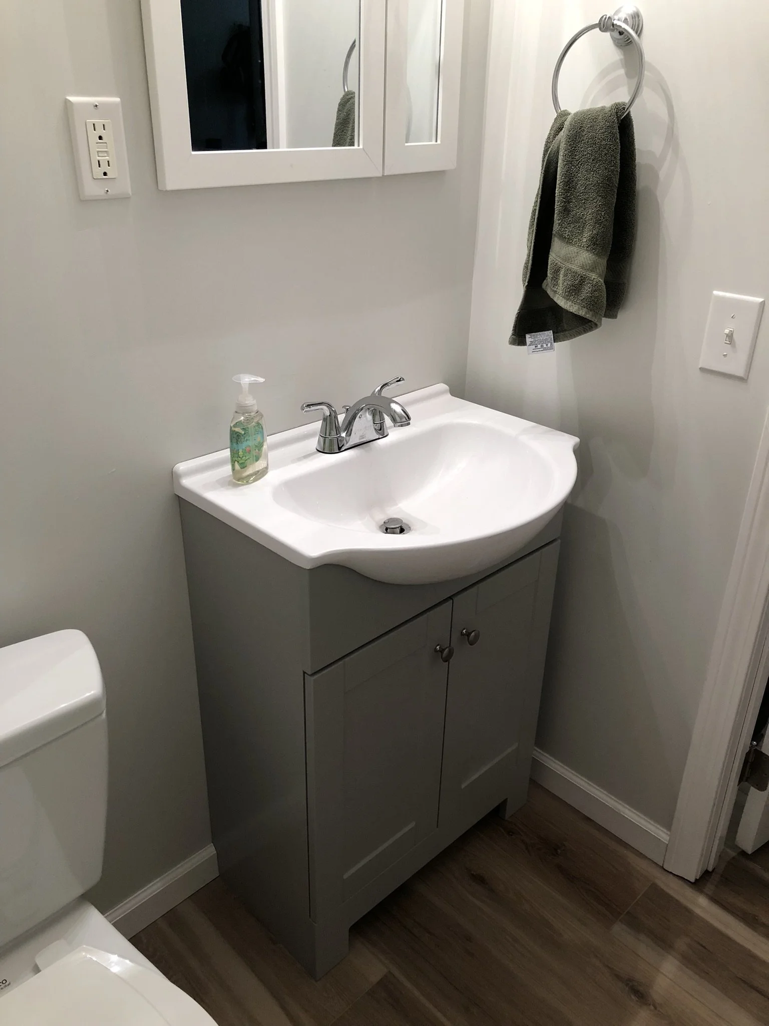 Fully utilizing this home's spacious, bright walk-out basement required the addition of a half-bathroom. A compact vanity maximizes space, while the extension of the luxury vinyl flooring from the adjacent Rec Room keeps cleaning and maintenance to a