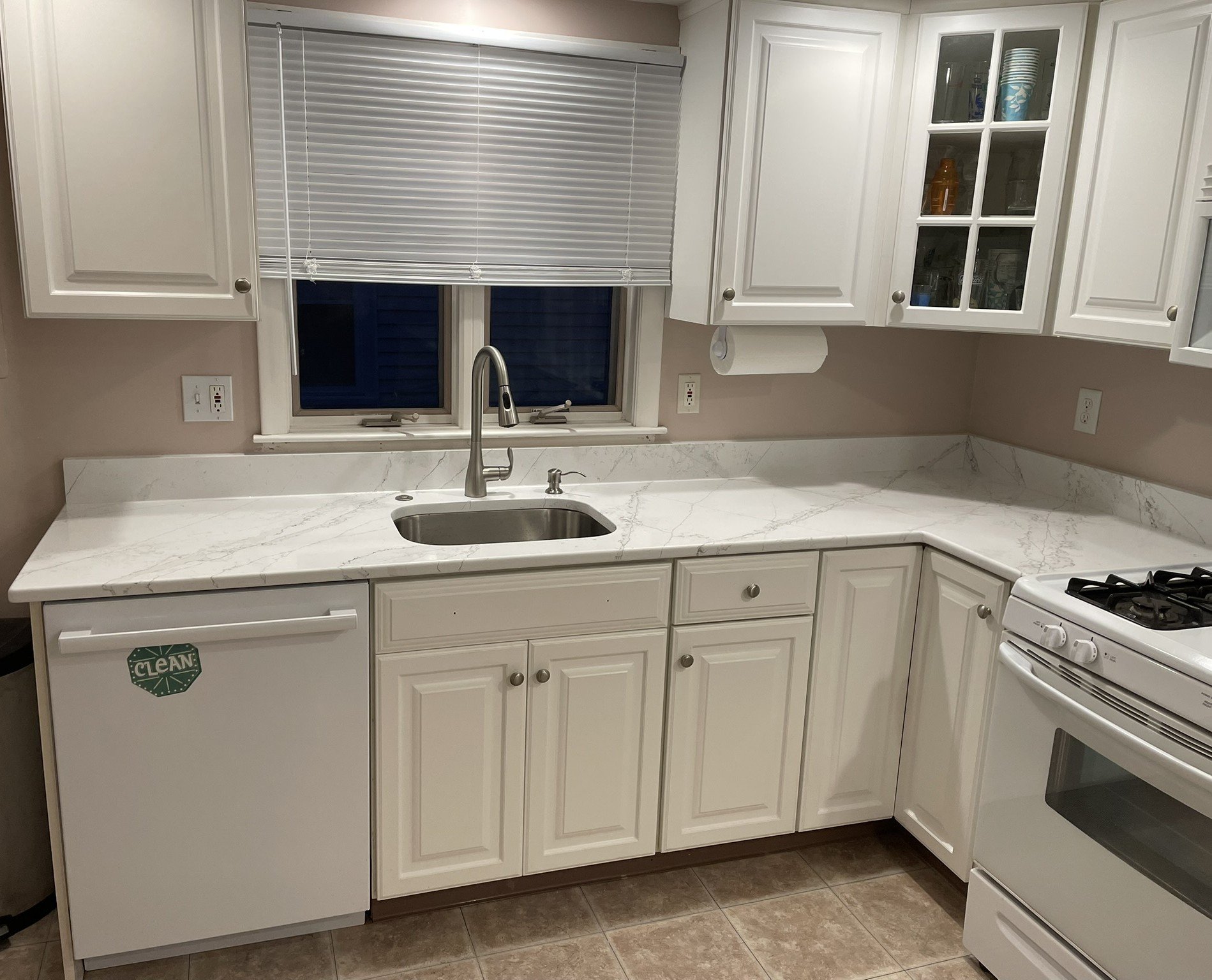 After adding new pantry cabinets (not shown here), a new quartz countertop and backsplash from Boston Fabrication was installed throughout, accompanied by a new deep-well sink, a high arc Moen faucet, and a countertop disposal switch.