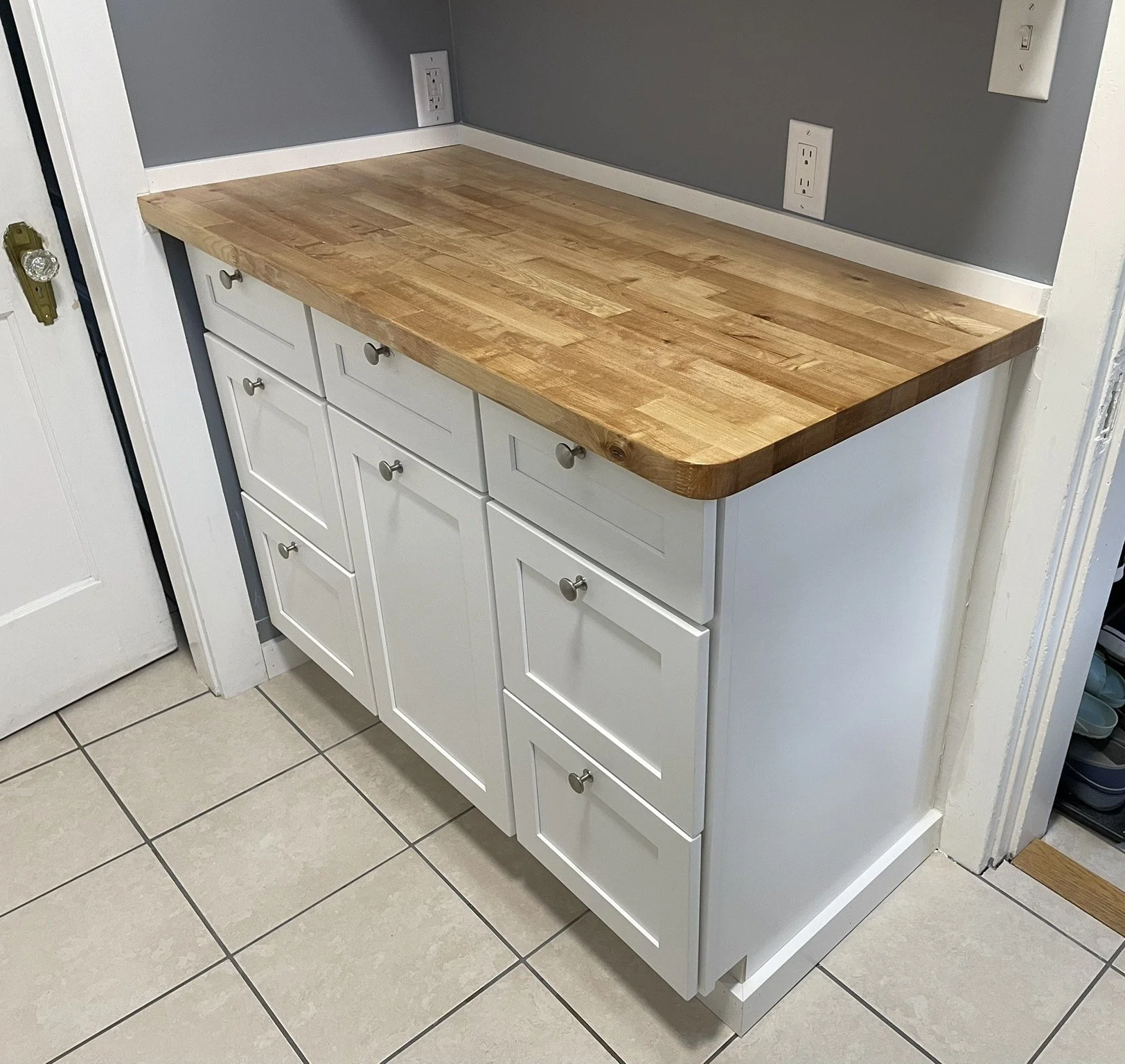 Laundry Room Cabinet and Countertop: Conversion of a back hall to a 1st floor laundry room was finally completed by the installation of hardwood cabinets (upper and lower) from Norfolk Kitchen and Bath. A butcher block countertop was custom fit and f