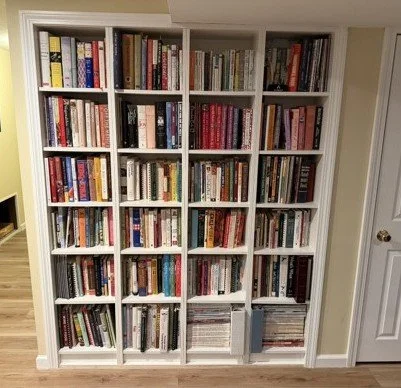 Built-In Bookcases: In this project, four ready-made 16"-wide bookcases were fashioned into an attractive and permanent built-in bookcase to house many  of the homeowner's extensive cookbook collection. The adjacent wall was pulled forward to create 