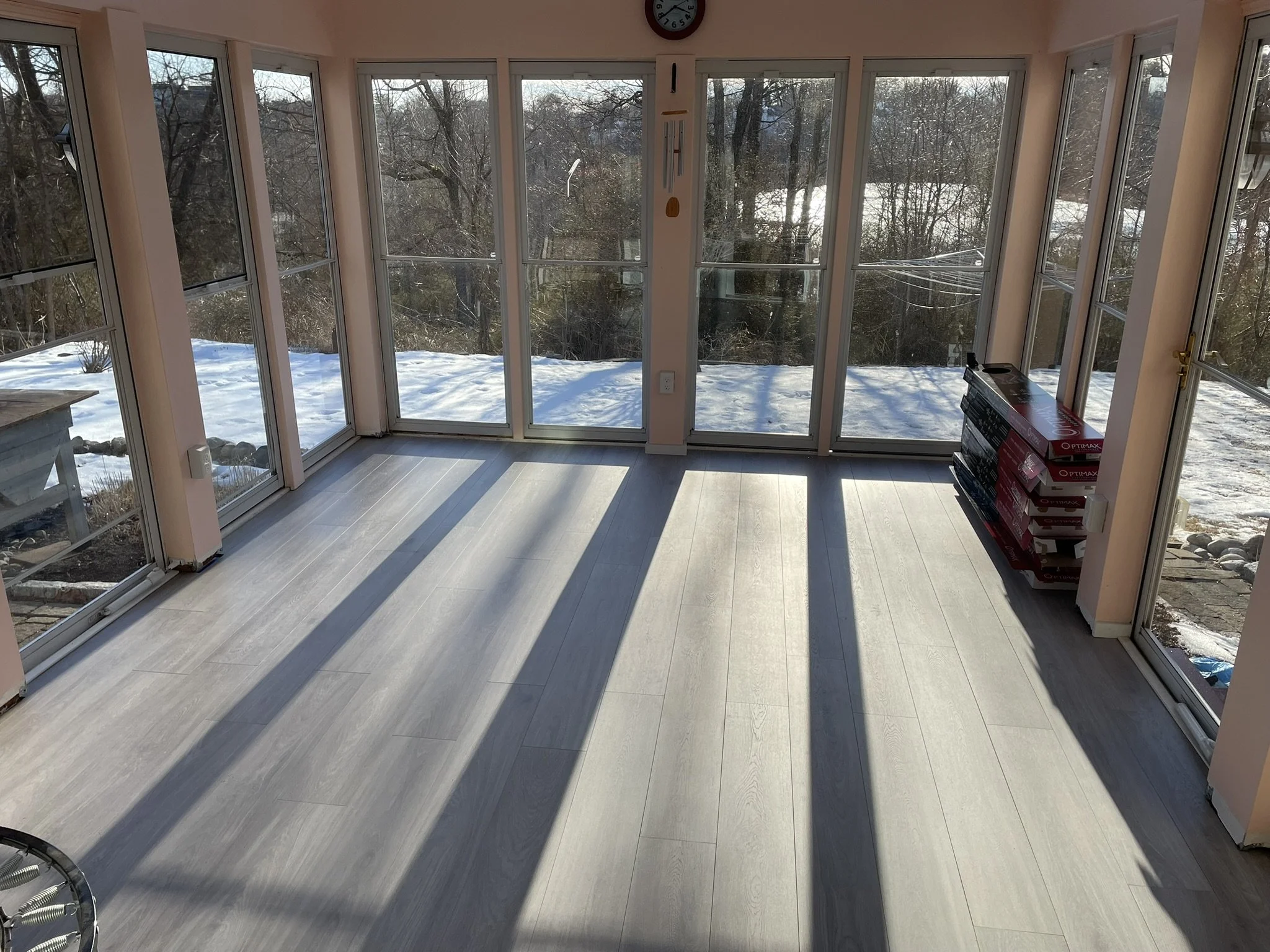 This spacious 3-season porch, overlooking well-tended gardens and a nearby pond was this homeowner's favorite spot. However, the bright sunlight had taken a toll on the original vinyl plank flooring. The heat from the sun had discolored some tiles ca