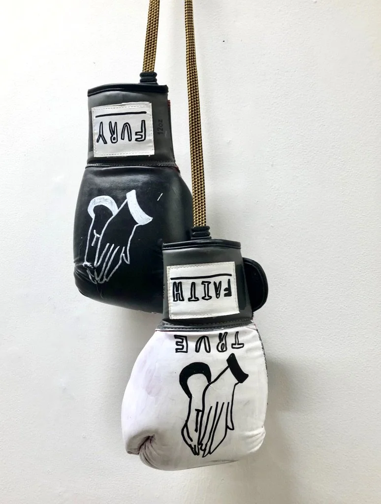 Pair of boxing gloves, one black and one white, hanging on a wall with the words "FUTURE" and "FAITH" written on them, and an illustration of two hands holding each other.