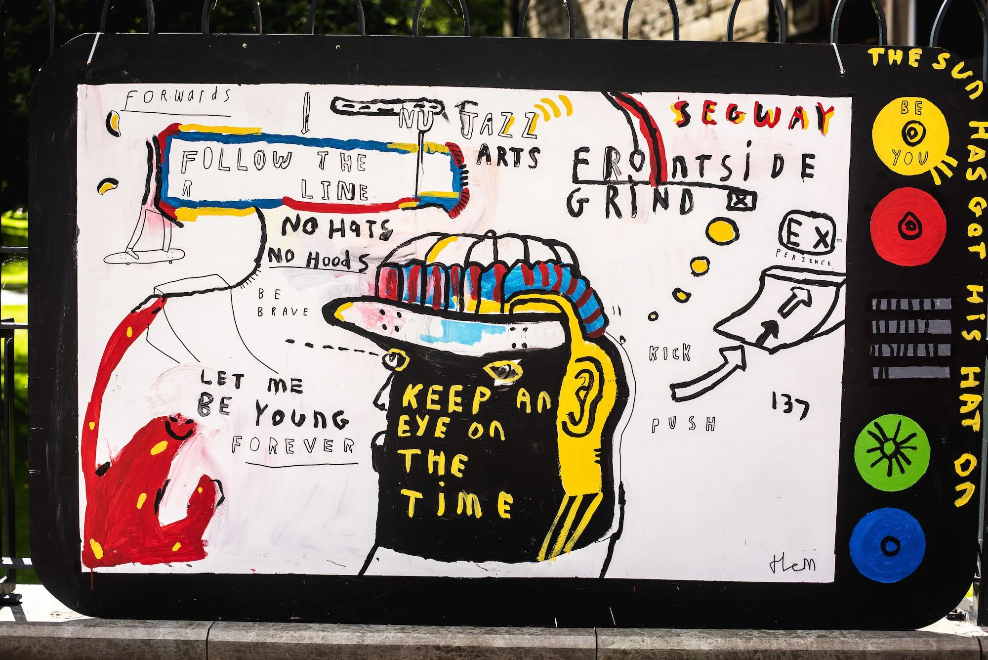 A colorful, hand-drawn mural featuring a person with a prominent head, with words like "Keep an eye on the time", "Follow the line", and phrases promoting bravery and youthfulness. The mural includes abstract imagery, arrows, and motivational words such as "Be you," "You" and "Have a go." The style is whimsical and expressive, with bold lines and bright colors.